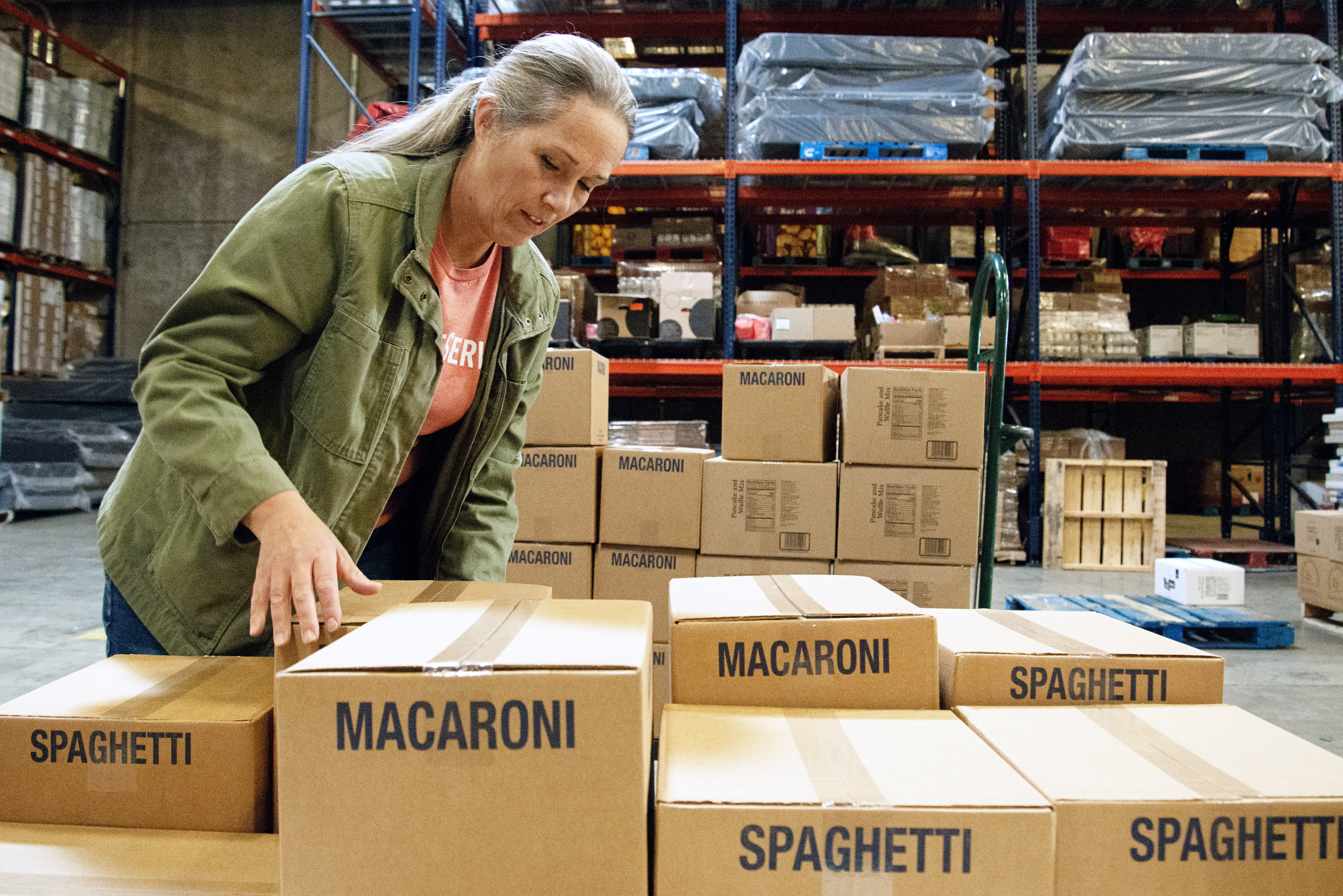 Tina Harding helps place boxed food items onto pallets for local organizations to eventually distribute in Aurora, Colo., on Thursday, Oct. 24, 2024. 