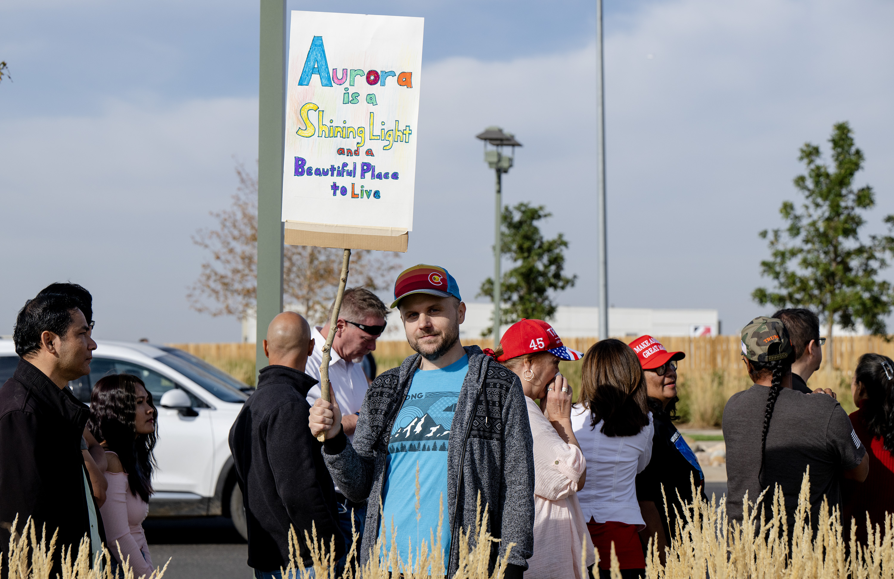 Luke Bollwerk, of Aurora, holds a sign as people wait in line for a Trump campaign rally at the Gaylord Rockies Resort and Convention Center, Friday, Oct. 11, 2024, in Aurora, Colo. “I’ve heard that’s a war zone, and that’s not the town I live in,” he says. “I wanted to let people know it’s beautiful” (Parker Seibold, The Gazette) (Parker Seibold, The Gazette)