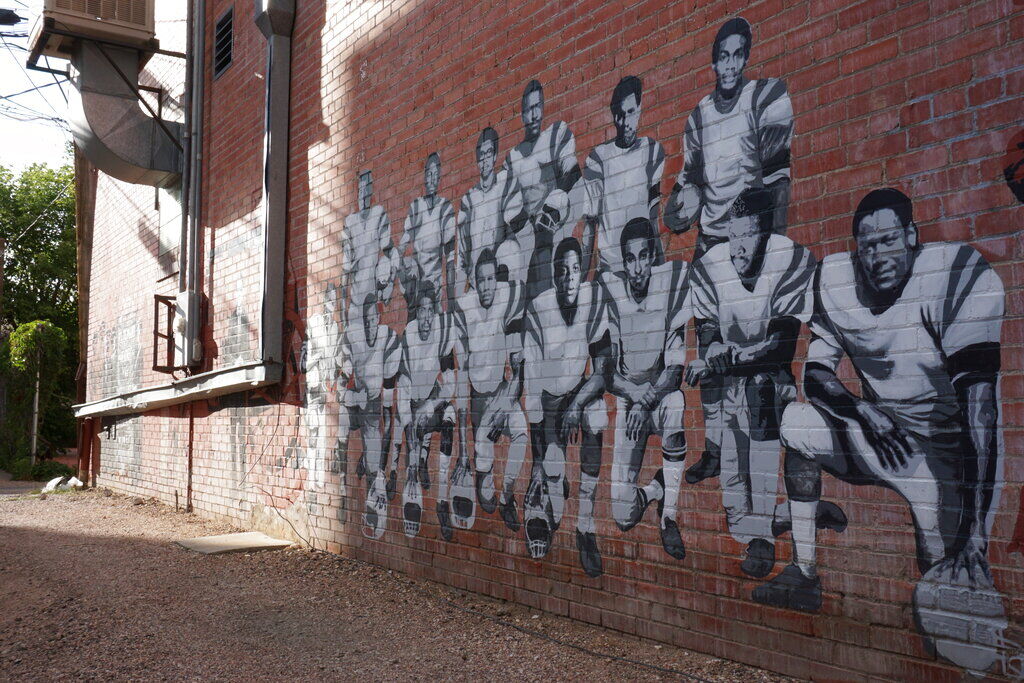 FILE PHOTO: This Wednesday, Sept. 11, 2019, photo shows part of an alleyway mural in downtown Laramie, Wyo., that honors the Black 14. The Black 14 were black athletes dismissed from the University of Wyoming football team in 1969 for seeking to protest racism by wearing black armbands in a game against Brigham Young University. The university dedicated a plaque honoring the group at War Memorial Stadium. (AP Photo/Mead Gruver) (Mead Gruver/AP)