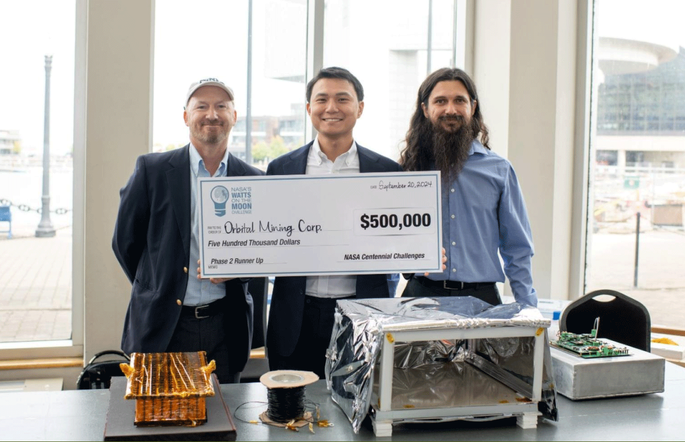 Orbital Mining Corporation’s leadership team with its lunar transmission and storage system. From left to right: Chris Tolton, CEO/co-founder; Ken Liang, CTO/co-founder; and, Raymundo Medina, chief technical adviser (Colorado School of Mines)