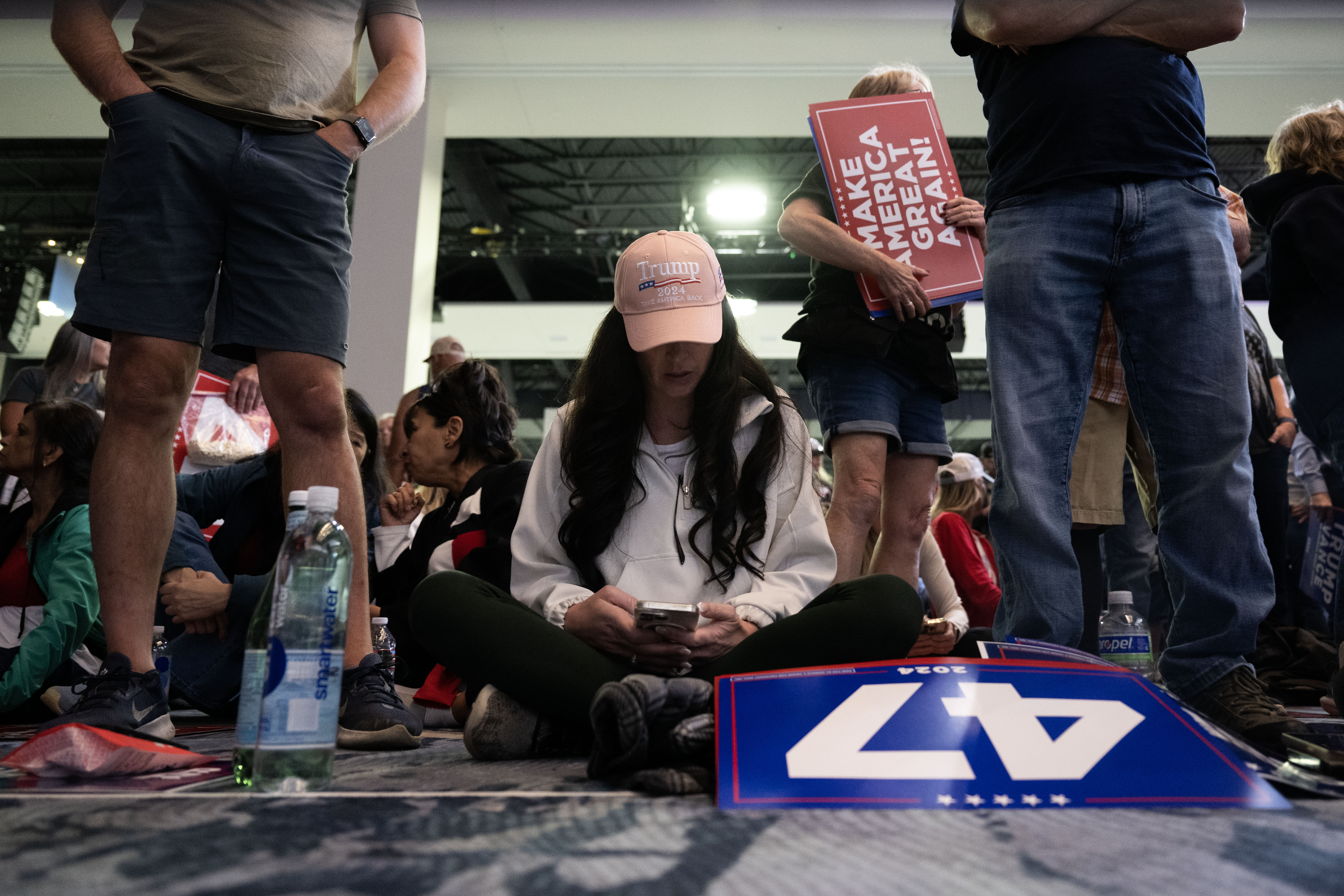 Trump fans sit on the floor in the Gaylord Rockies Resort and Convention Center in Aurora as they wait for the start of a rally on Friday, Oct. 11, 2024. (Stephen Swofford, Denver Gazette) (Stephen Swofford Denver Gazette)