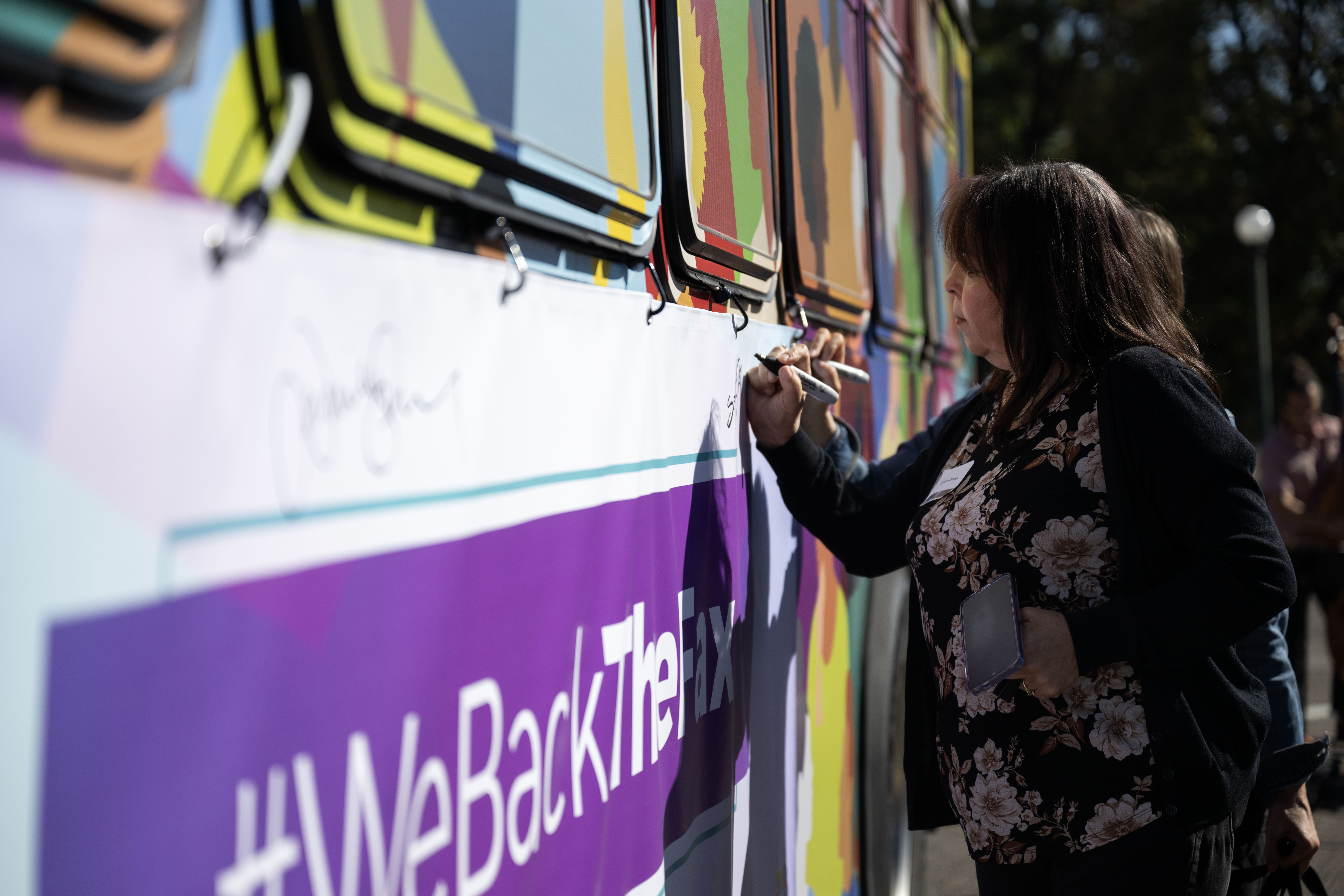 Sandra Ortega, with Hope Communities, signs a banner on the side of a bus during the groundbreaking ceremony on Friday, Oct. 4, 2024 for a $280M transit improvement project that will introduce Denver’s first bus rapid transit project to transform how bus service operates on East Colfax Avenue. (Stephen Swofford, Denver Gazette) (StephenSwoffordPhotographerstephen.swofford@gazette.comhttps://secure.gravatar.com/avatar/1ddcaf11c5d70eaa58546ddc4e038687?d=mm&r=g)