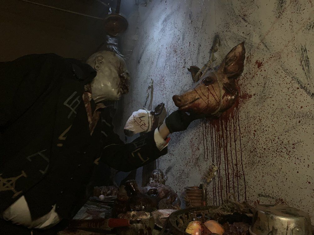 A monster interacts with a pig head prop at The Ritual Haunted House in Englewood, Colorado. (Courtesy photo, The Ritual Haunted House.)