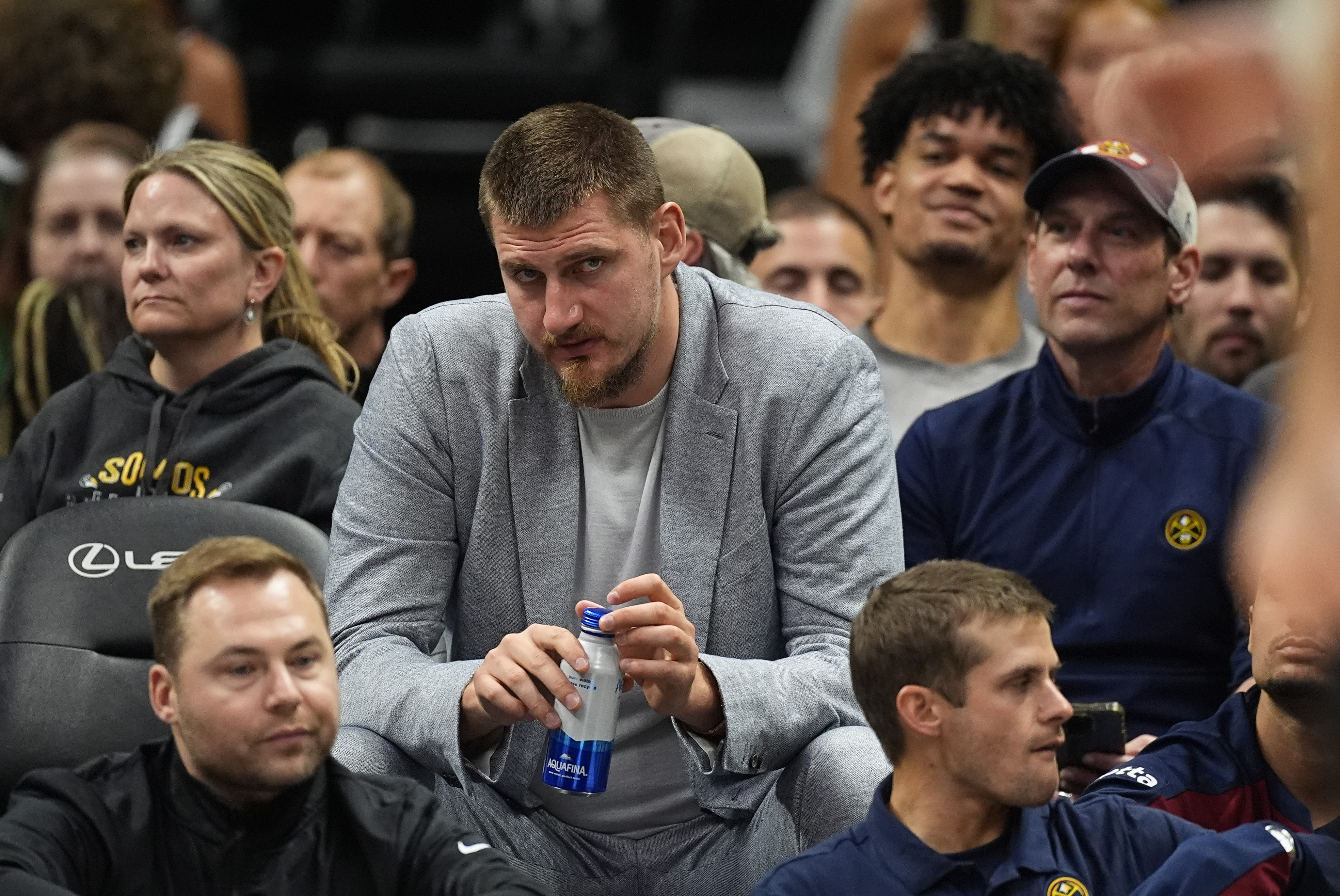 Dressed in street clothes since he did not play, Denver Nuggets center Nikola Jokic looks on from a courtside seat in the second half of an NBA preseason basketball game against the Oklahoma City Thunder Tuesday, Oct. 15, 2024, in Denver. (AP Photo/David Zalubowski) (David Zalubowski)