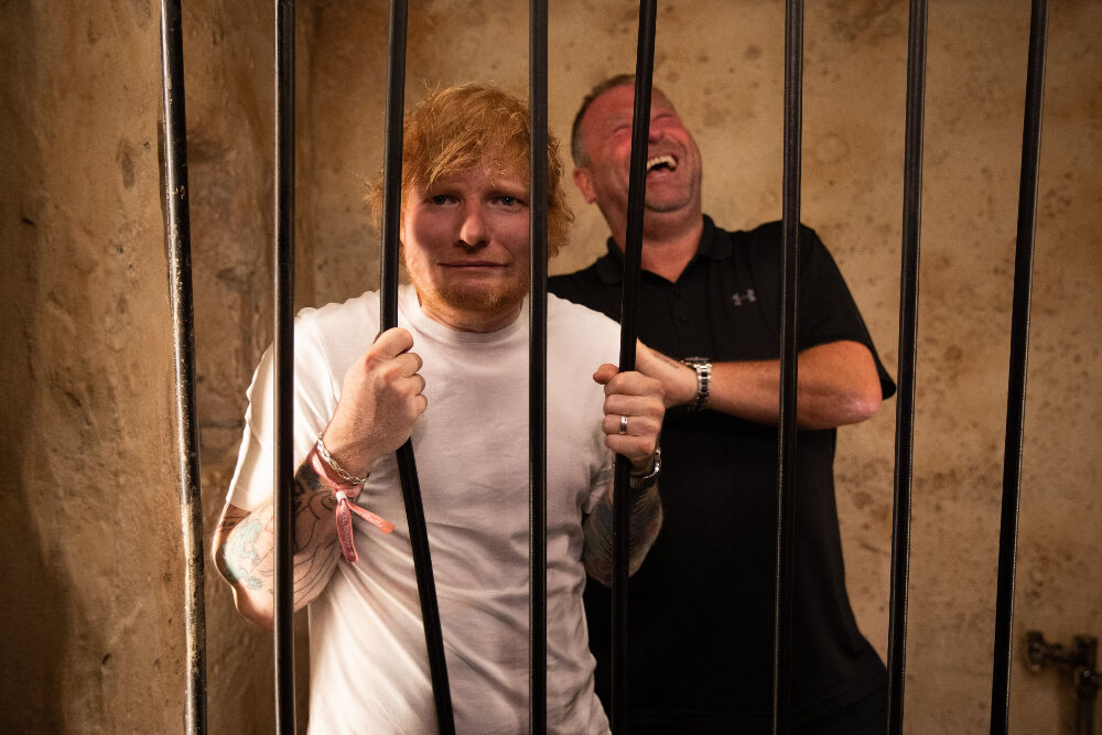 Ed Sheeran had fun in 'jail' before his Aug. 19, 2023, concert in Denver while visiting the Casa Bonita restaurant and arcade in Lakewood. When Sheeran posted this photo to Twitter, Casa Bonita employee Apryl Edwards responded on behalf of the restaurant: 'I love your face in the jail, but I think I like Kevin laughing more. I love everything do. You're so funny. It's nice to get to see you have some fun because I know you work extremely hard every day!' The man with Sheeran is known as 'Security Kev – the guy who's been keeping Ed Sheeran safe since 2015.' (Courtesy Ed Sheeran HQ)