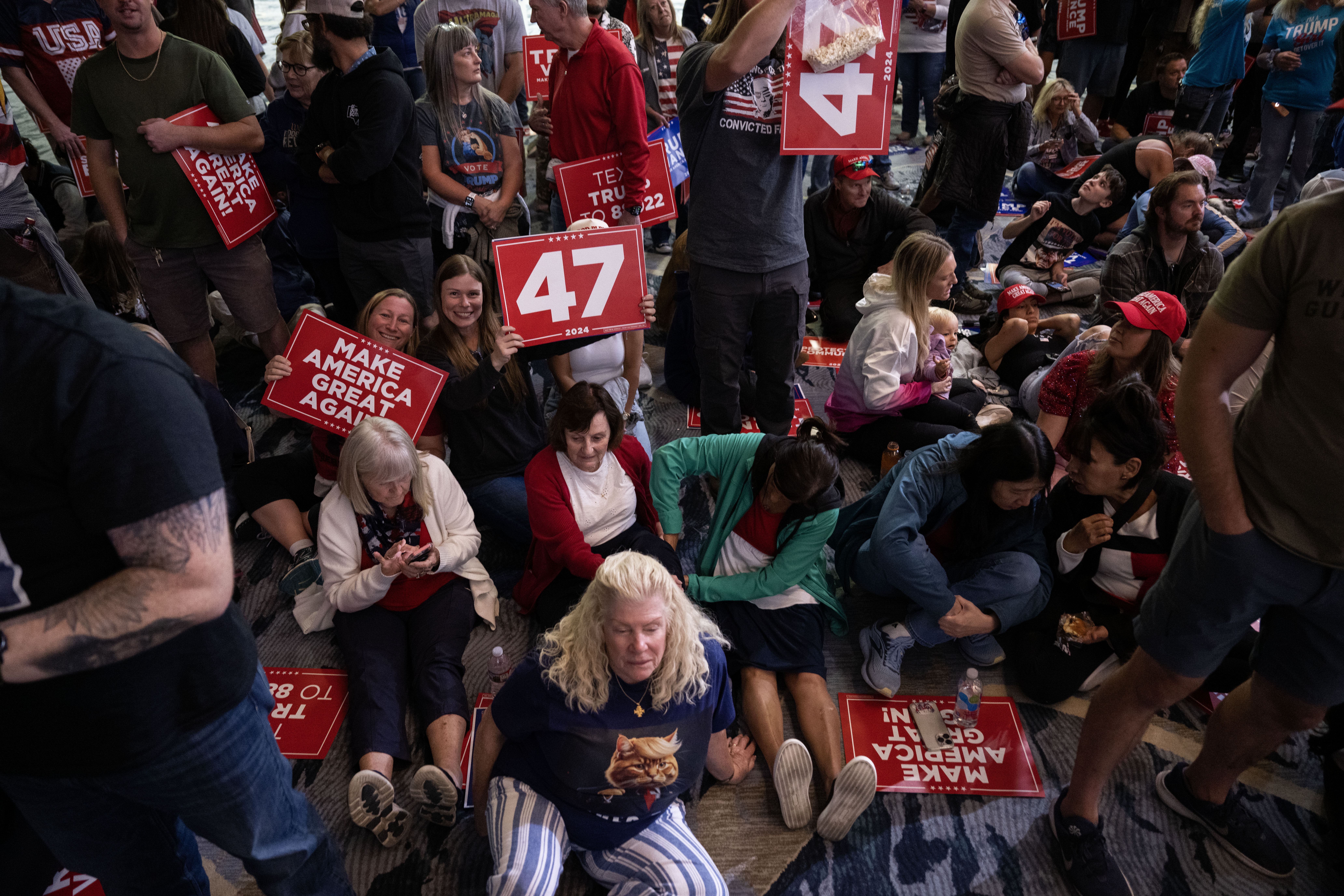 People rest on the floor as they wait for the start of a trump rally at the Gaylord Rockies Resort and Convention Center in Aurora on Friday, Oct. 11, 2024. (Stephen Swofford, Denver Gazette) (Stephen Swofford Denver Gazette)