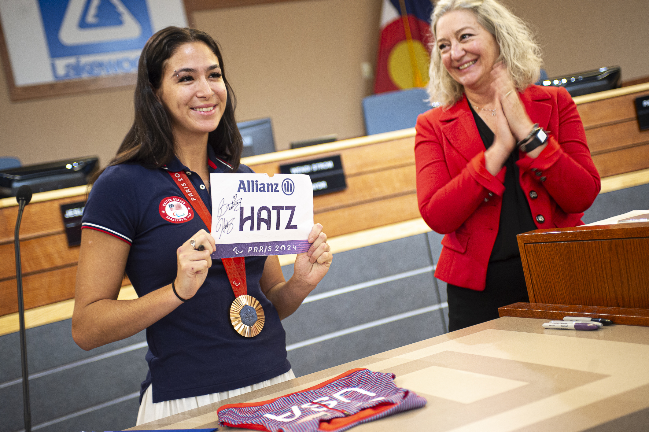 Paralympic bronze medalist Beatriz Hatz shows off her bib from the 2024 Paralympic Summer Games in Paris as Lakewood Mayor Wendi Strom looks on. Hatz presented her official bib and jersey to the city as a thank you for their support throughout her athletic career. They will be displayed at the Lakewood Civic Center atrium. (DeborahSmithGeneral Assignment Reporterdeborah.smith@denvergazette.comhttps://denvergazette.com/content/tncms/avatars/5/cb/928/5cb9281a-1916-11ef-a934-ff8eced4f17d.8e406ef28428e7c4f743743e38d7aa35.png)