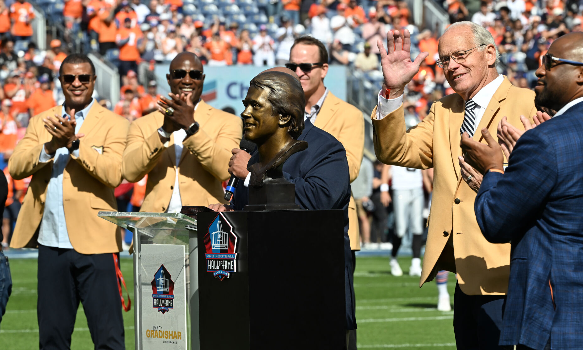 Recent Broncos Hall of Fame inductee Randy Gradishar (right) was honored before the game against the Raiders at Empower Field at Mile High on Sunday, Oct. 6, 2024. Many Broncos Hall of Famers were on hand for the ceremony, including Steve Atwater, DeMarcus Ware, and Peyton Manning (background, left to right) (Jerilee Bennett The Gazette)