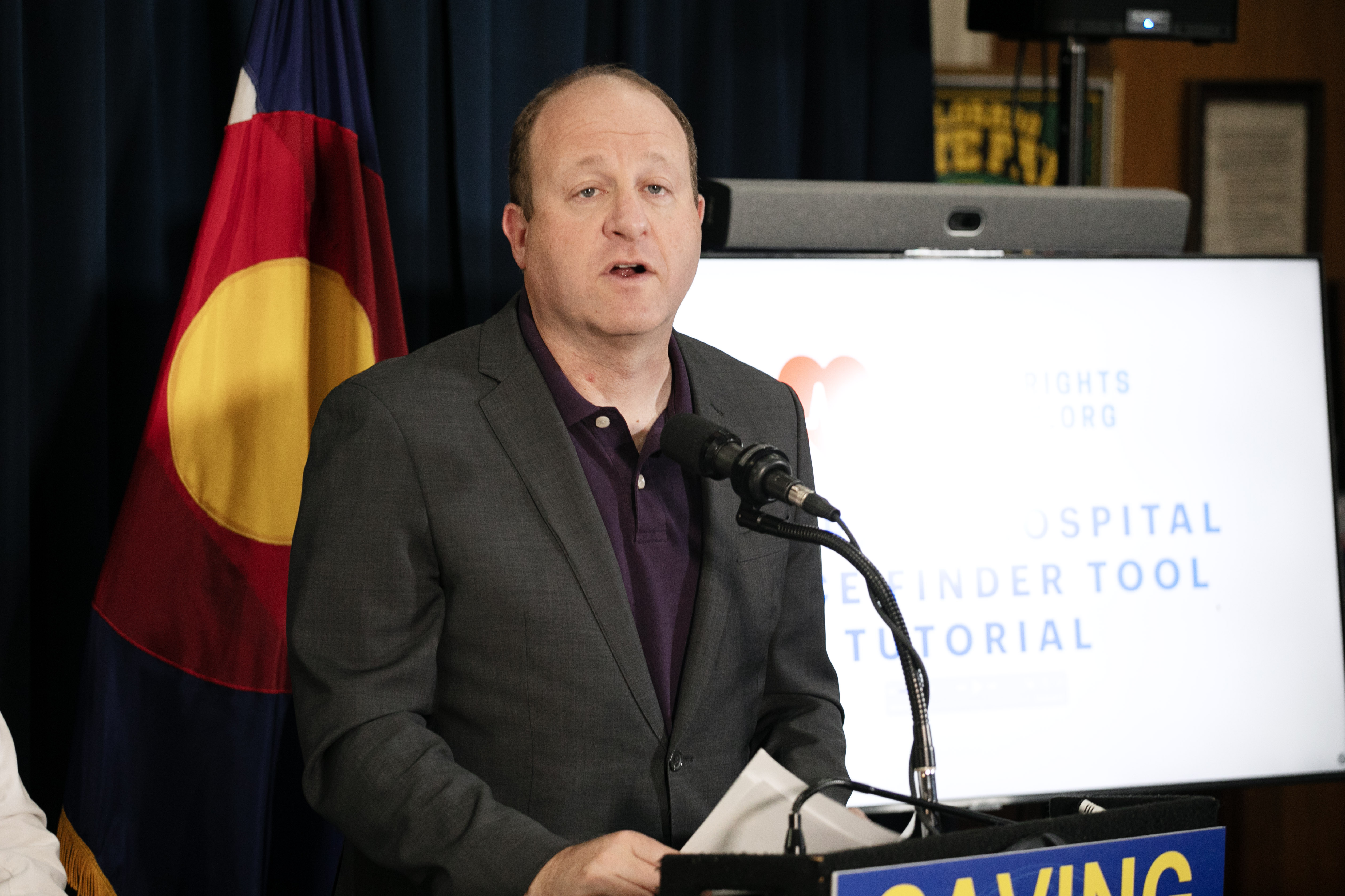 Gov. Jared Polis addresses members of the media about the launch of a new online database for Colorado healthcare patients to compare costs from various providers in the state created by the non-profit, Patient Rights Advocate, from the Colorado State Capitol on Tuesday, Oct. 22, 2024. Costs of procedures and treatment can vary as much as, 