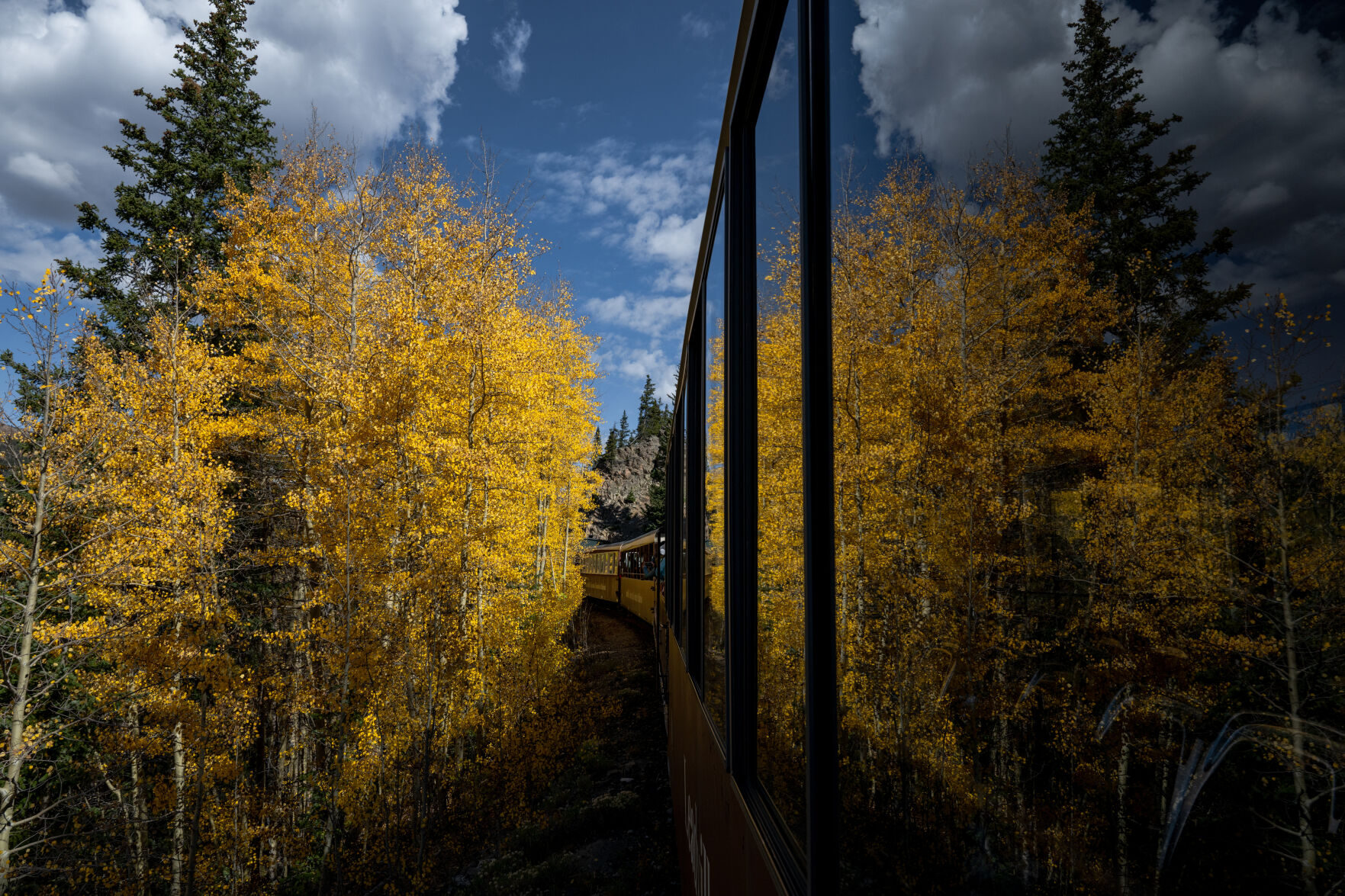 Yellow aspens are reflected on the windows of a railcar of the Leadville Railroad last month. As passengers take in the views of the changing trees and surrounding mountains, the conductor narrates the colorful history of the area. (Parker Seibold, The Gazette)