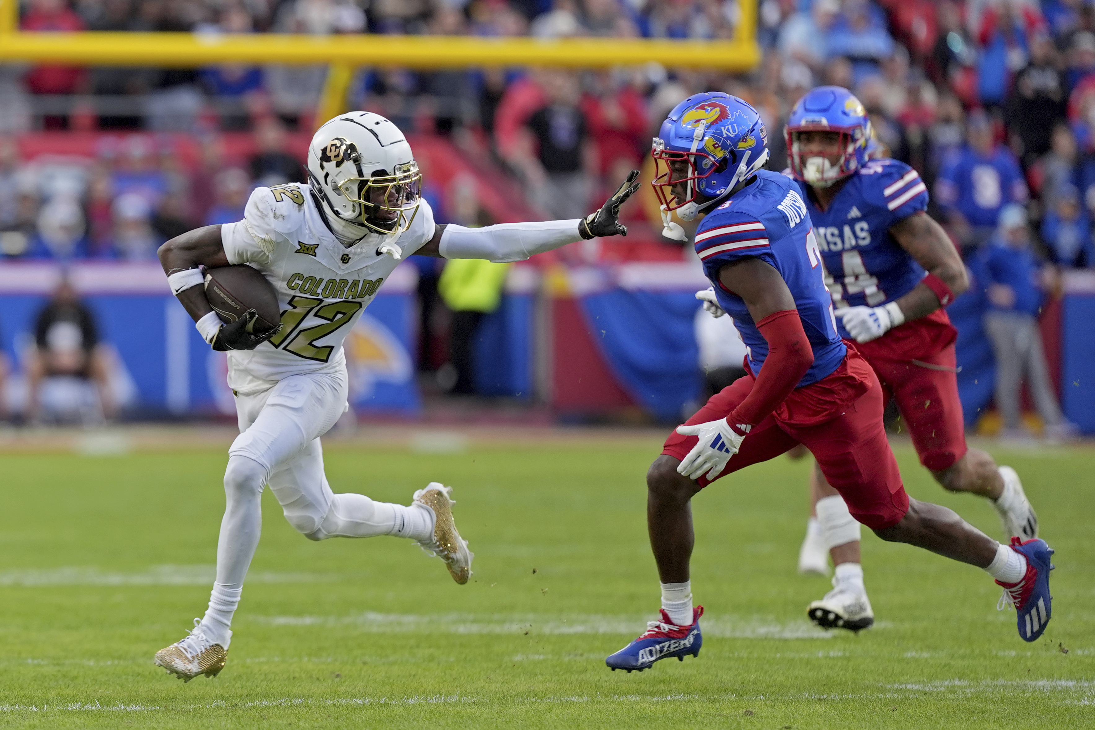 Colorado wide receiver Travis Hunter (12) pushes away Kansas cornerback Mello Dotson (3) as he runs for a first down during the first half of an NCAA college football game, Saturday, Nov. 23, 2024, in Kansas City, Mo. (AP Photo/Charlie Riedel) (Charlie Riedel)