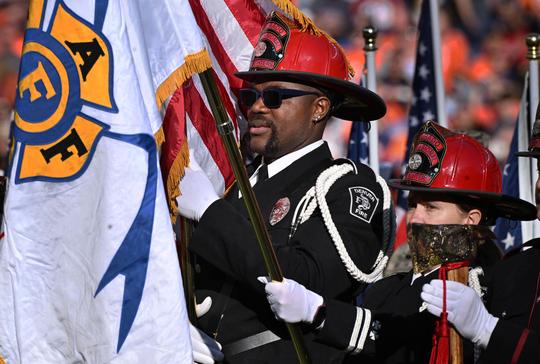 Former Bronco Wesley Duke (center) holds the U.S. flag while participating in an honor guard before a game against the Falcons on Sunday, Nov. 17, 2024. Duke is now a member of the Denver Fire Dept. (Jerilee Bennett,The Gazette)