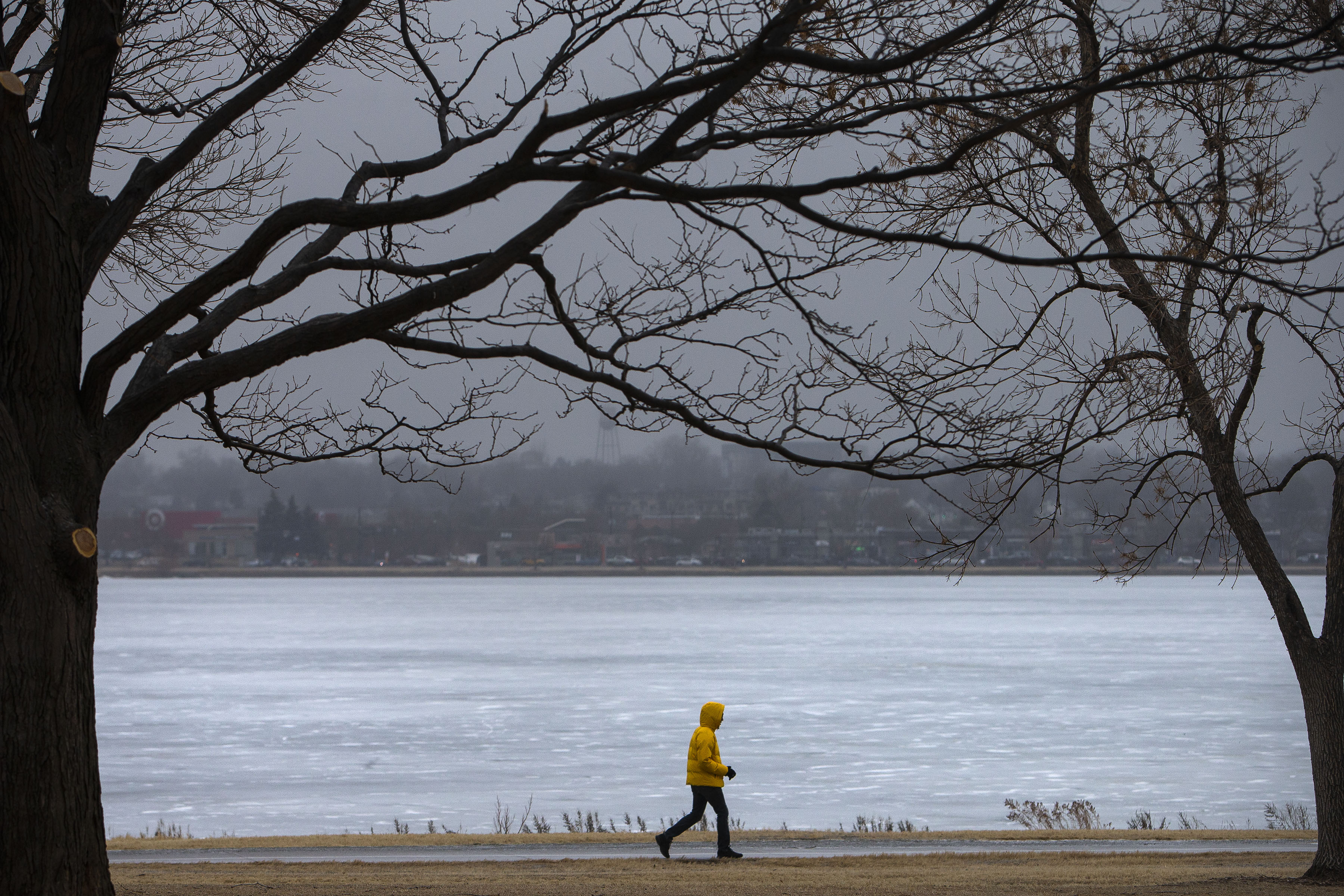 FILE PHOTO: A pedestrian walks past a frozen Sloan's Lake on Wednesday, Jan. 19, 2022, in Denver. The neighborhood is one of the few parts of Denver that still has carriage lots, a plot of land found in the center of a block once used for parking horse-drawn carriages. (Timothy Hurst, The Gazette)