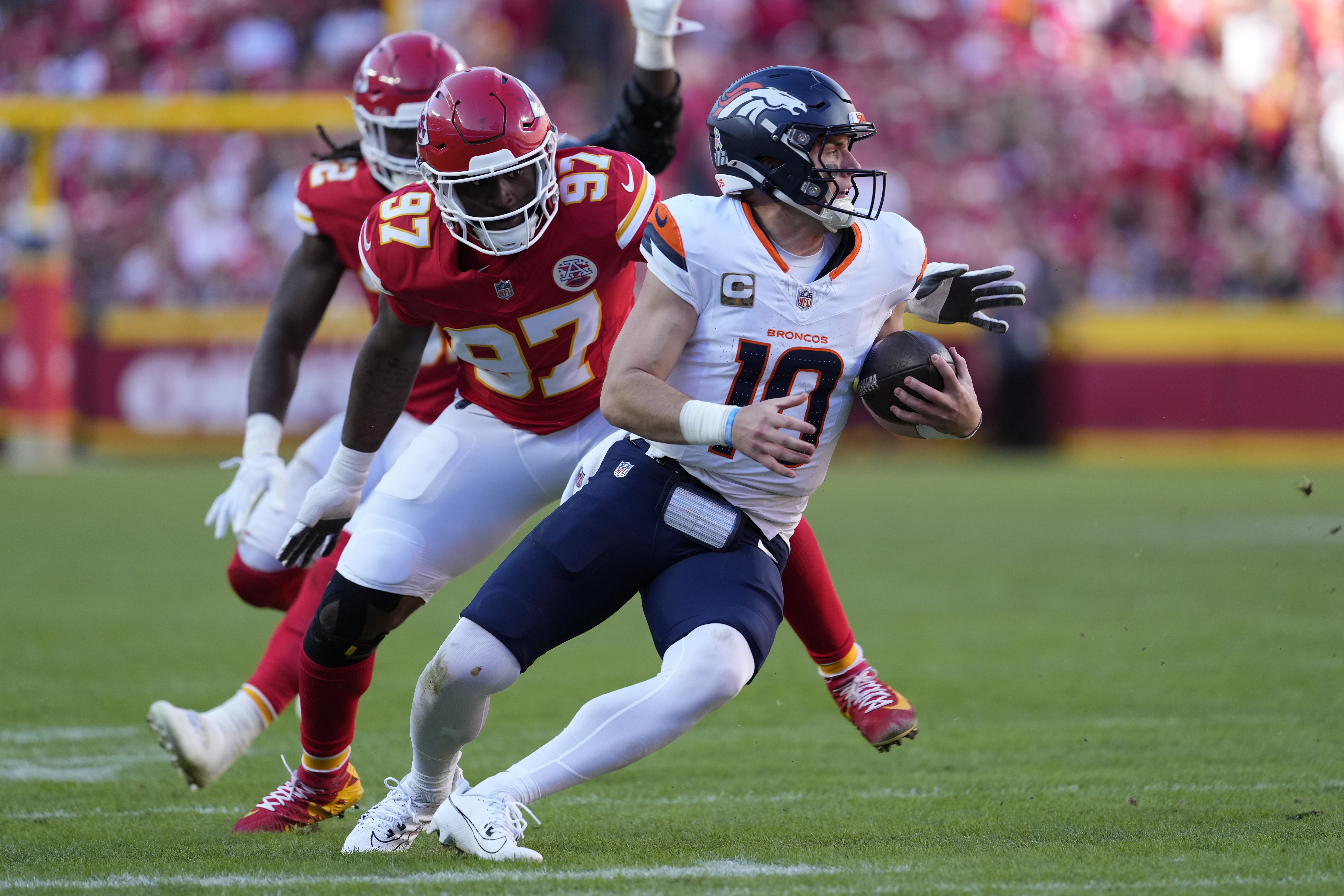 Denver Broncos quarterback Bo Nix (10) scrambles away from Kansas City Chiefs defensive end Felix Anudike-Uzomah (97) during the second half of an NFL football game Sunday, Nov. 10, 2024, in Kansas City, Mo. (AP Photo/Ed Zurga) (Ed Zurga)