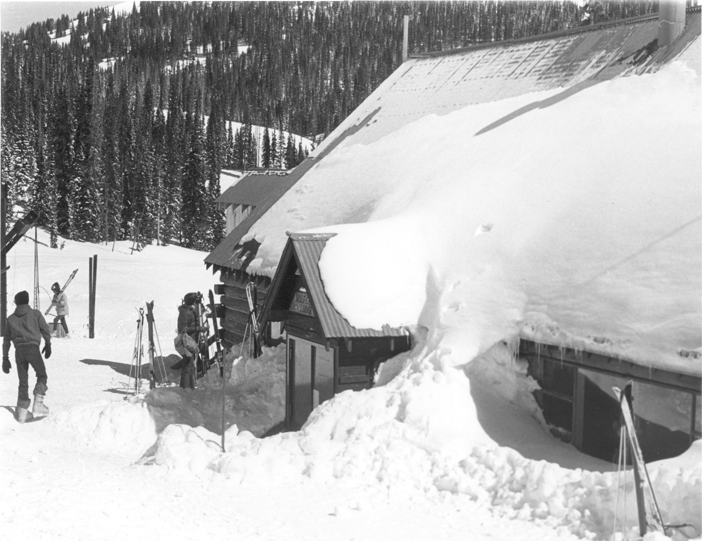 Skiers walk around the base area at Wolf Creek Ski Area in southwestern Colorado, circa 1970, with large amounts of snow on the building's roof. (Courtesy, Rio Grande County Museum)