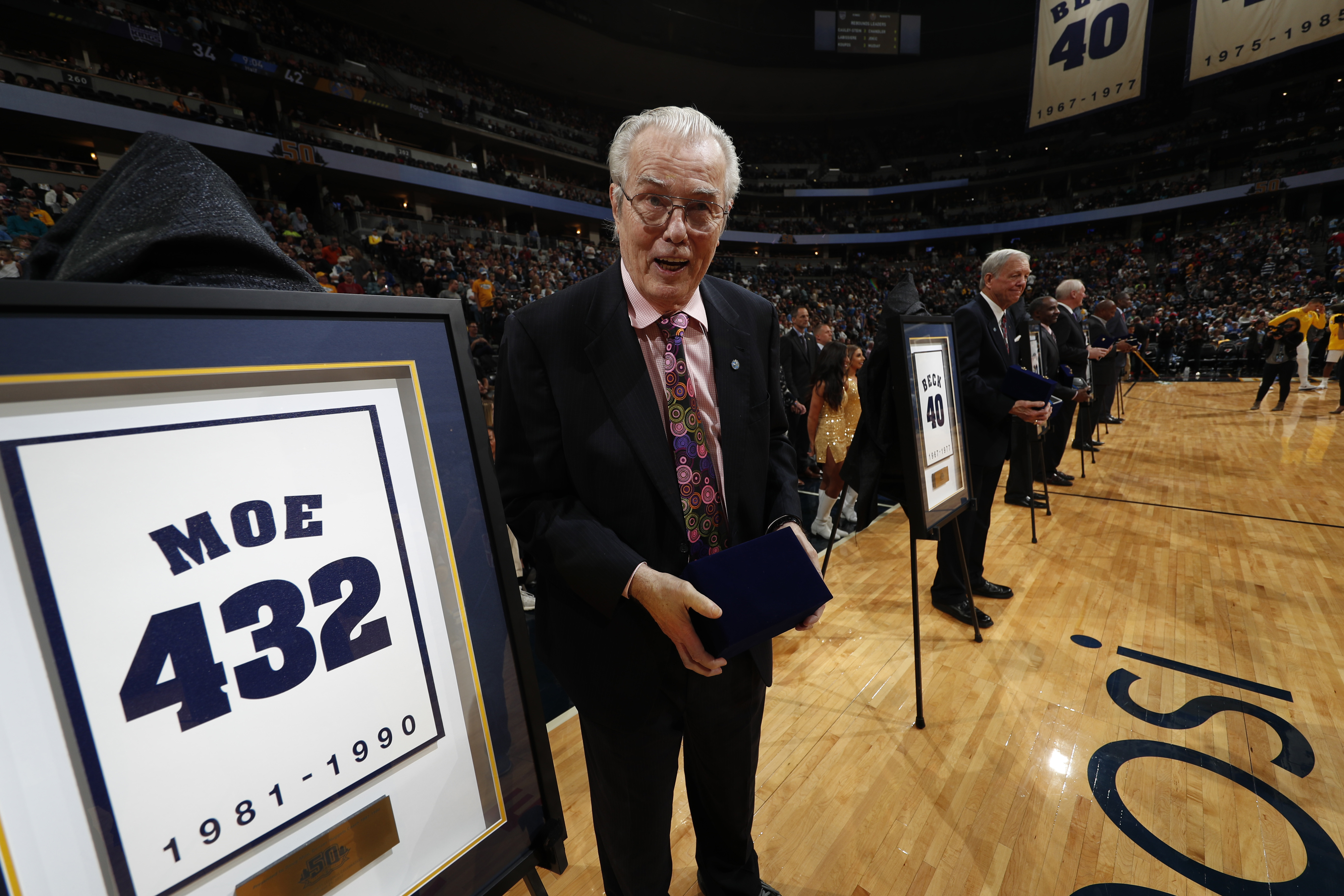 Retired Denver Nuggets head coach Doug Moe displays gifts after being feted as part of the team's 50th anniversary celebration before the second half of an NBA basketball game Saturday, Oct. 21, 2017, in Denver. The Nuggets won 96-79. (AP Photo/David Zalubowski) (David Zalubowski)