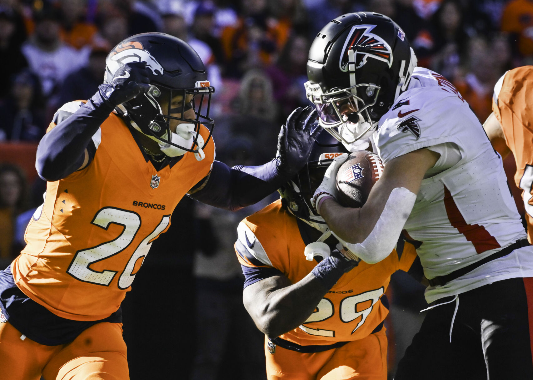 Denver Broncos safety Devon Key (26) and Denver Broncos cornerback Ja'Quan McMillian (29) stop Atlanta Falcons wide receiver Drake London (5) from getting to the end zone during a game against the Falcons at Empower Field at Mile High on Sunday, Nov. 17, 2024.