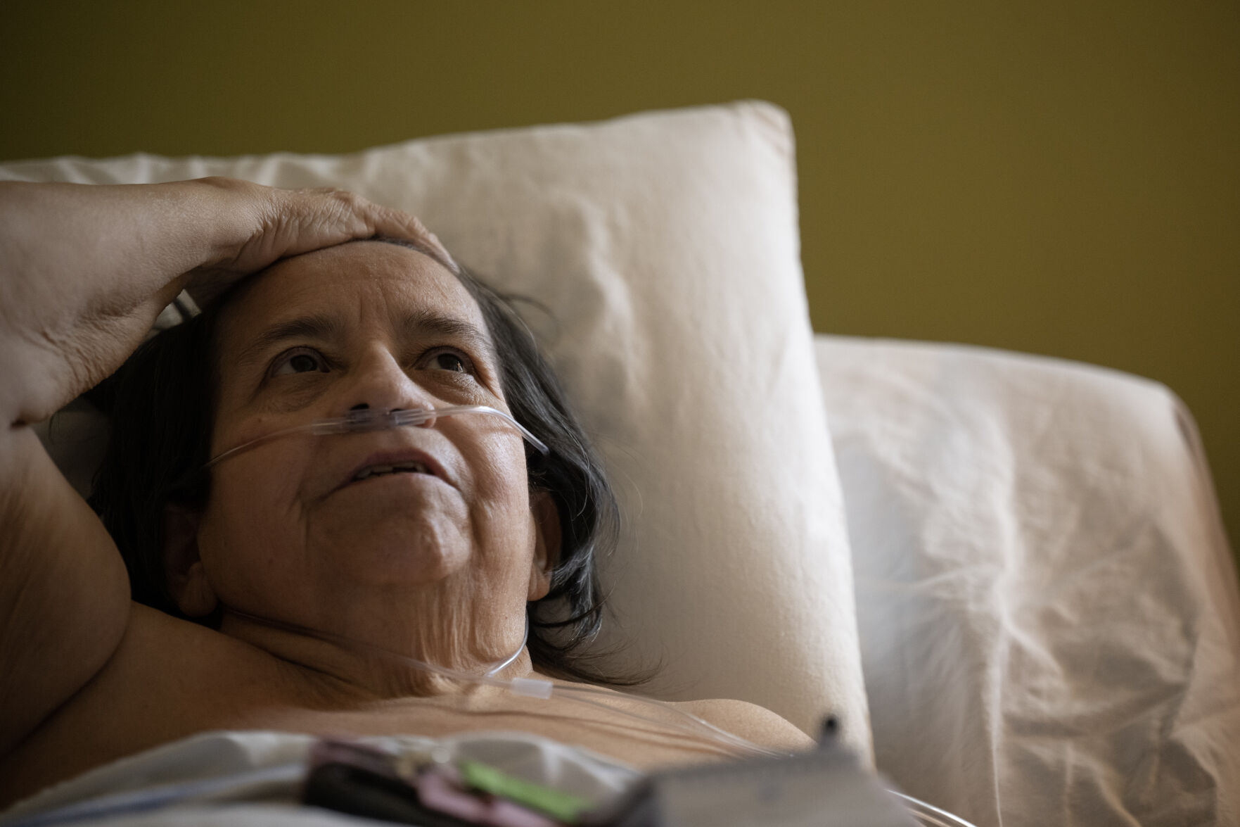 Louise Apodaca, bedridden due to multiple health issues, combs her hair back with her hand while discussing the stresses of organizing her own in-home care while at her apartment in a Denver Housing Authority high rise. (Timothy Hurst, The Gazette)