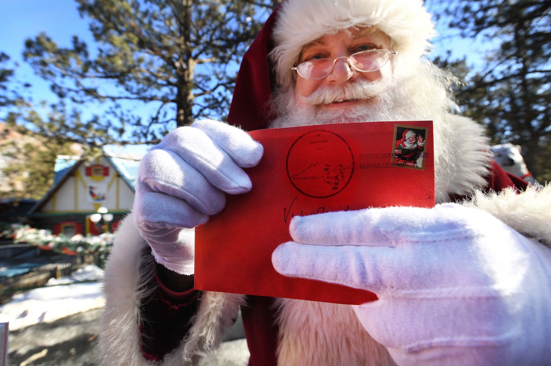 Santa’s Workshop North Pole in Cascade and the United States Postal Service designed a postmark that features the longtime Pikes Peak region attraction. Santa takes a few minutes out of his busy day to display the new postmark at Santa’s Workshop North Pole during a news conference Nov. 26. (Photo by Jerilee Bennett)