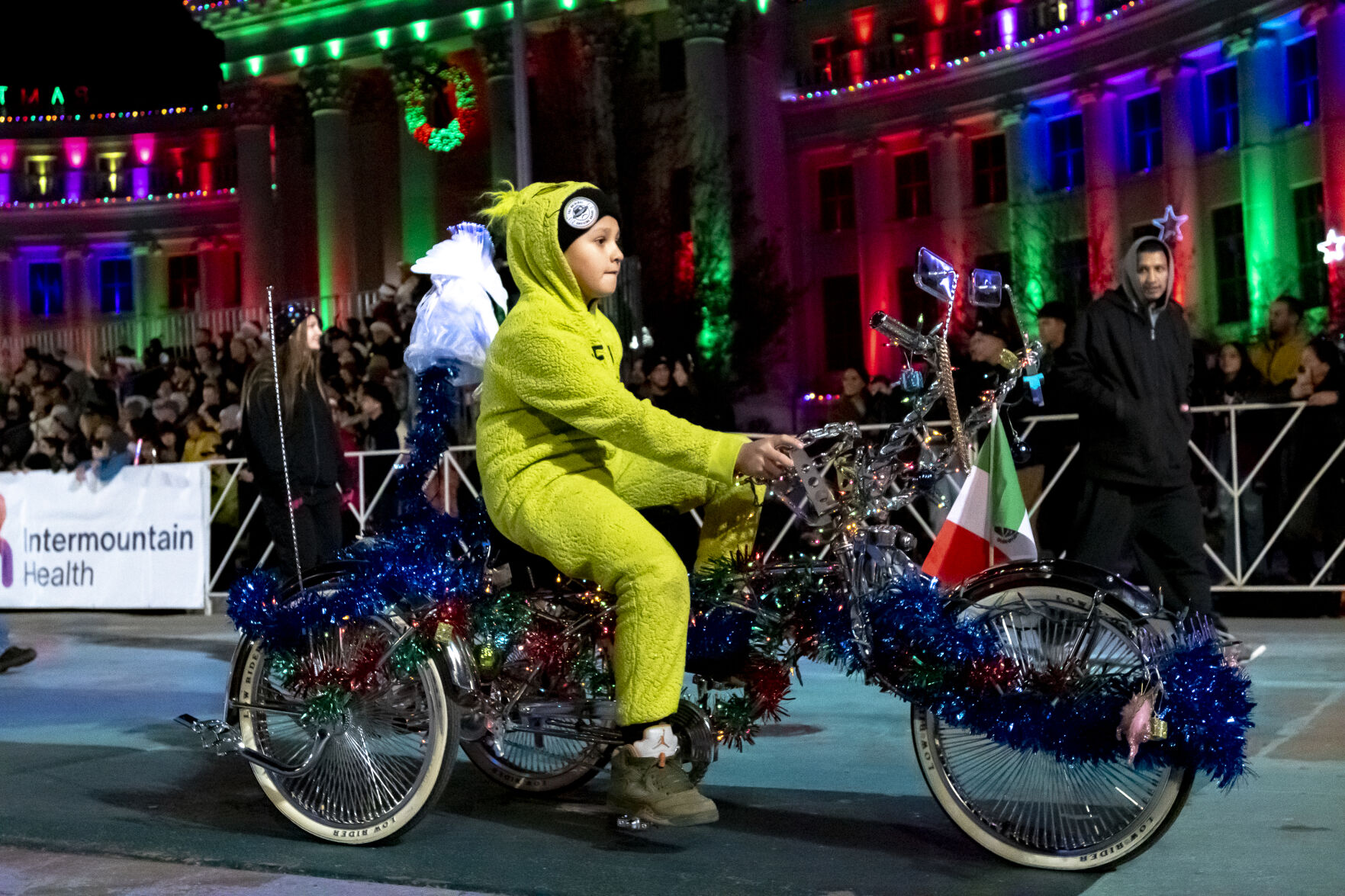 A young lowrider dressed as a grinch rides his bicycle past the Denver City Council building on Bannock Street in Denver on Saturday, Dec. 7, 2024 during the 9NEWS 50th Anniversary Parade of Lights. (Laura Domingue/Special to the Gazette) (LAURA DOMINGUE/Special to The Denver Gazette)