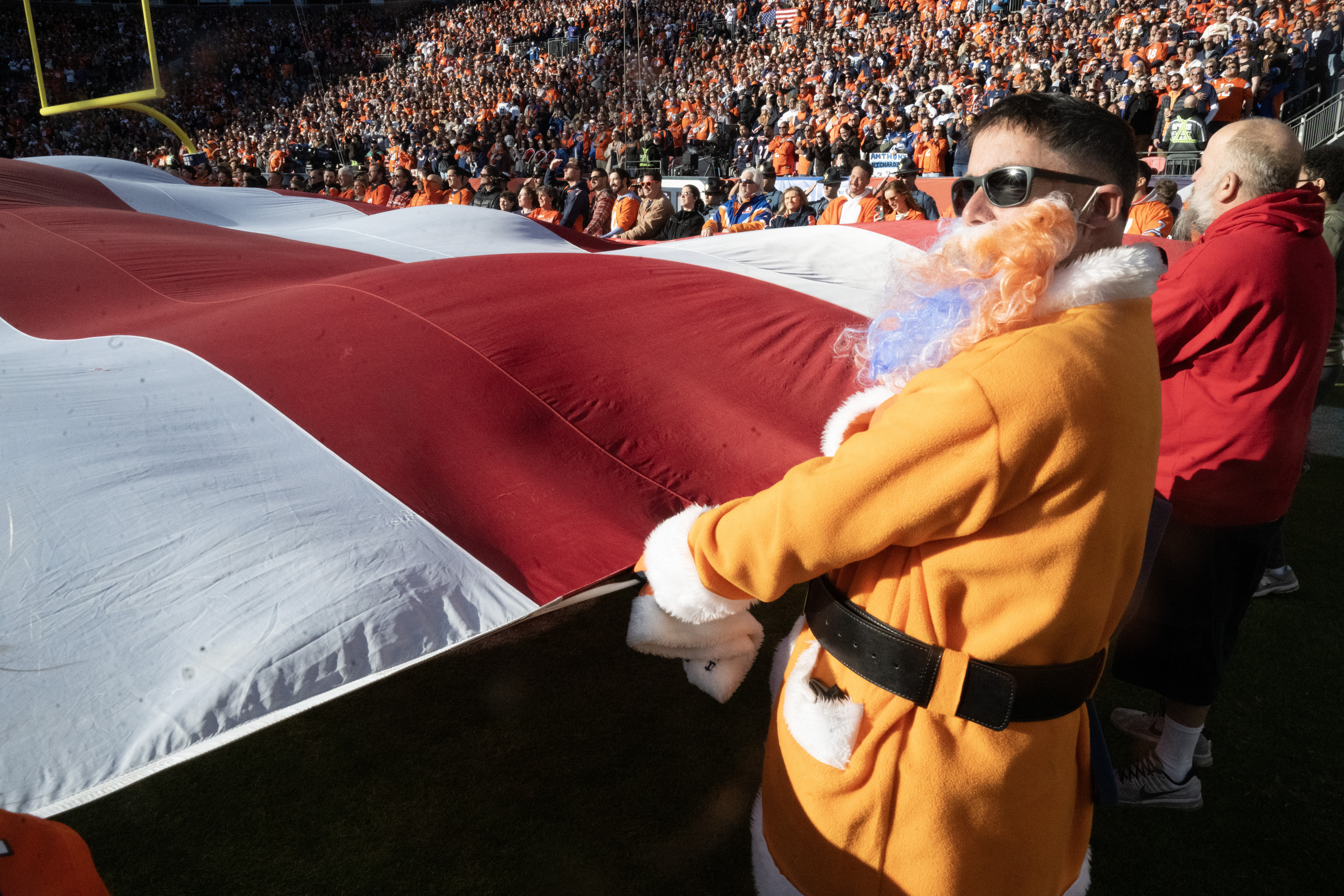 A Bronco version of Santa Claus helps with the giant flag during the national anthem before the Broncos/Colts game on Sunday, Dec. 15, 2024. (Jerlee Bennett)