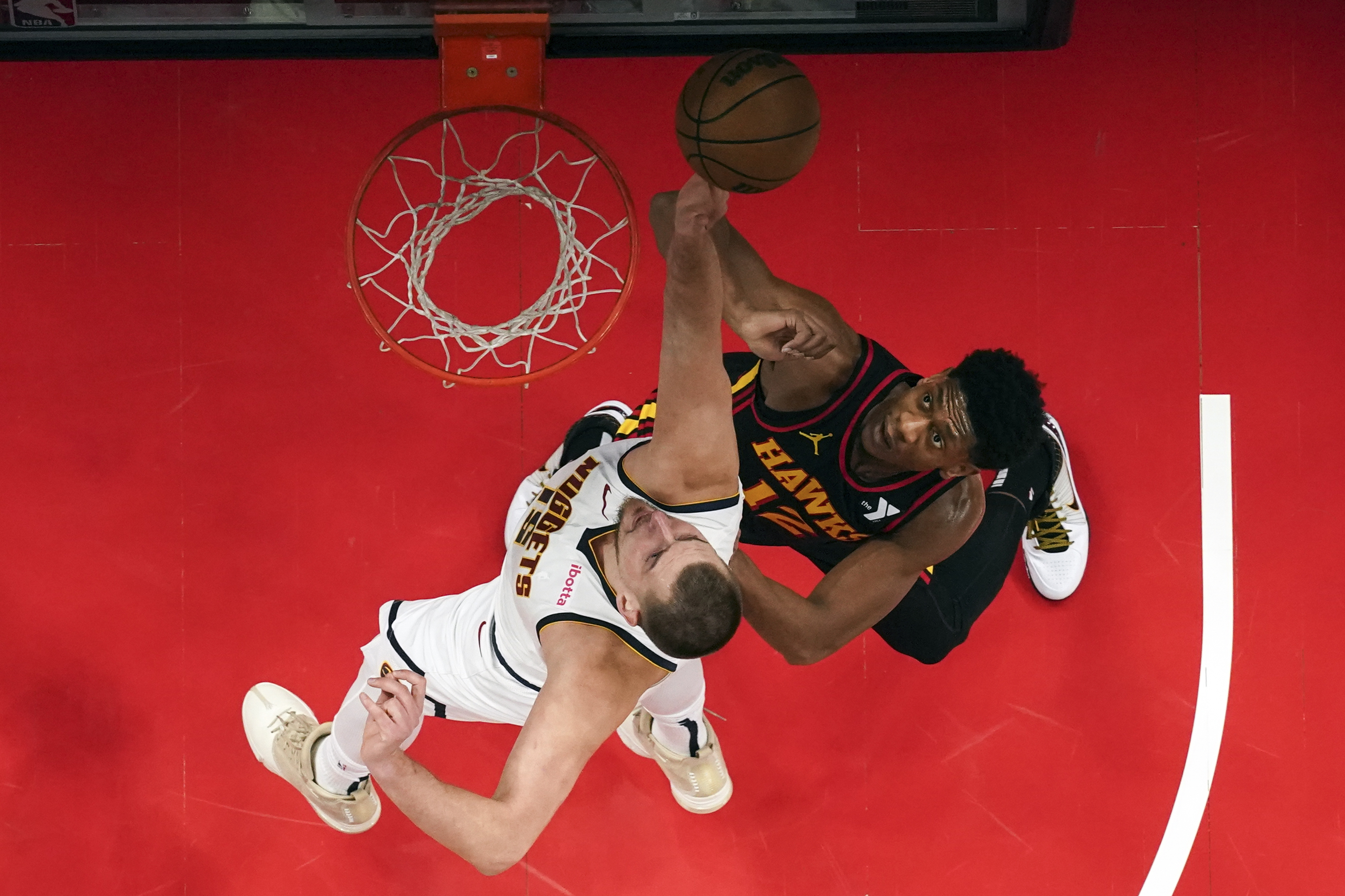 Denver Nuggets center Nikola Jokic (15) and Atlanta Hawks forward De'Andre Hunter (12) battle for a rebound in the first half of an NBA basketball game, Sunday, Dec. 8, 2024, in Atlanta. (AP Photo/John Bazemore) (John Bazemore)