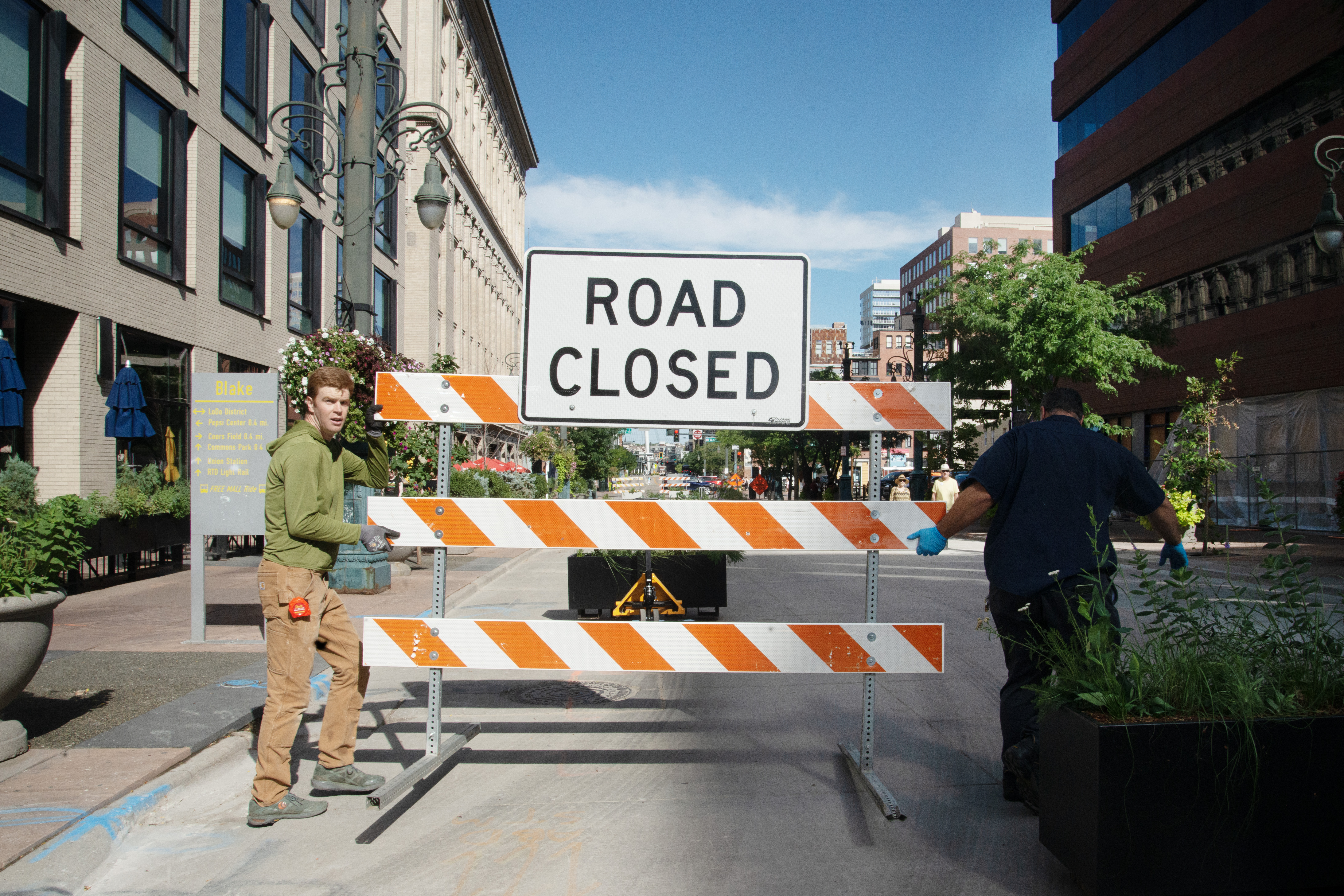 Brandon Johnson, left, and Ray Ortiz remove road closure signs from a newly re-opened section of the 16th Street Mall on Thursday, Aug. 29, 2024. 