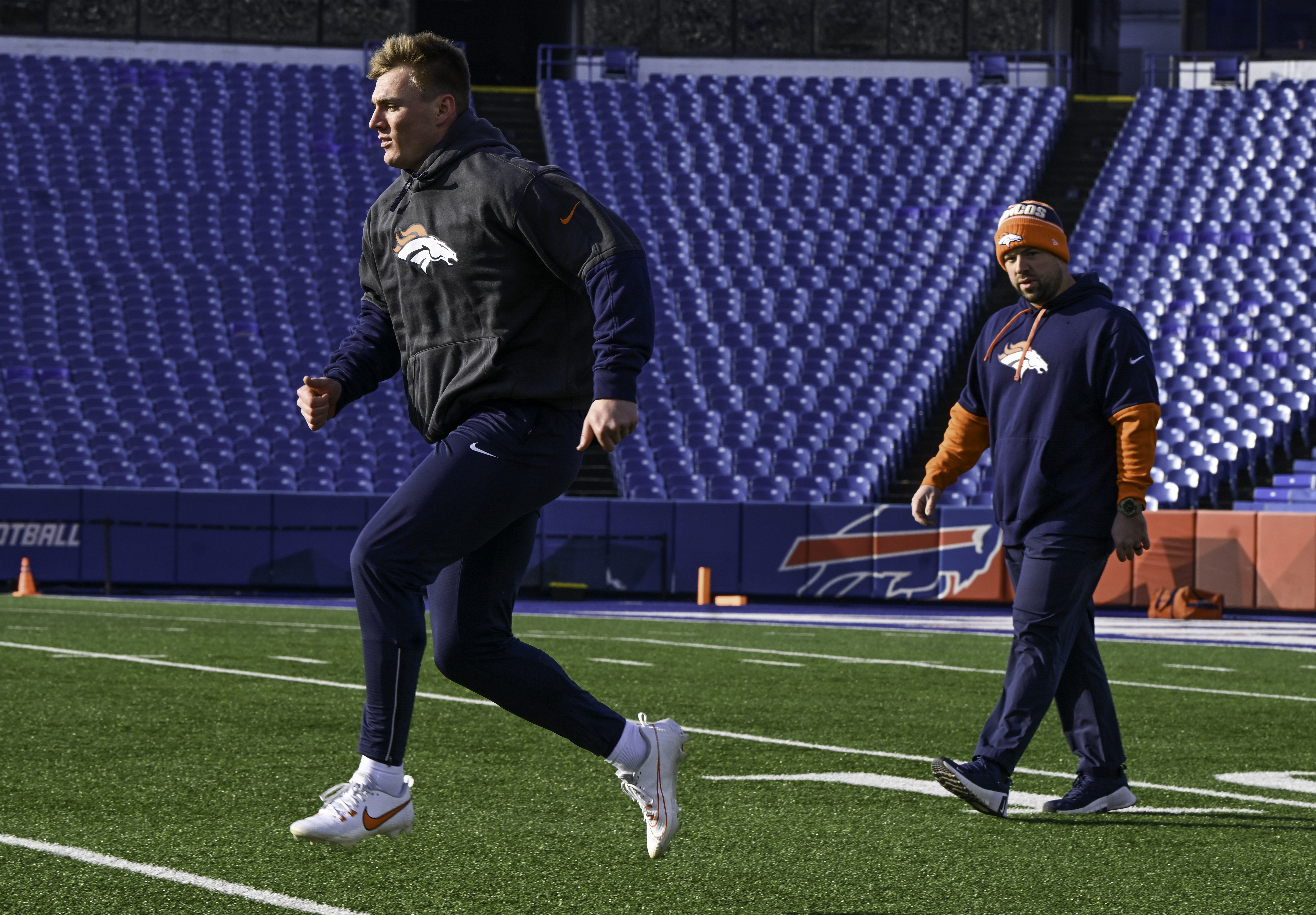 Denver Broncos quarterback Bo Nix (10) warms up with Shaun Snee, Broncos strength and conditioning coach,. before the wild card playoff game between the Broncos and the Bills at Highmark Stadium in Buffalo on Sunday, January 12, 2025. (Jerilee Bennett,The Gazette)