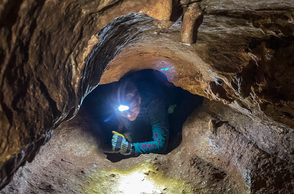 Alyssa Mulzer makes her way through a tight tunnel on the Cave of the Winds caving tour. Photo Credit: Spencer McKee.