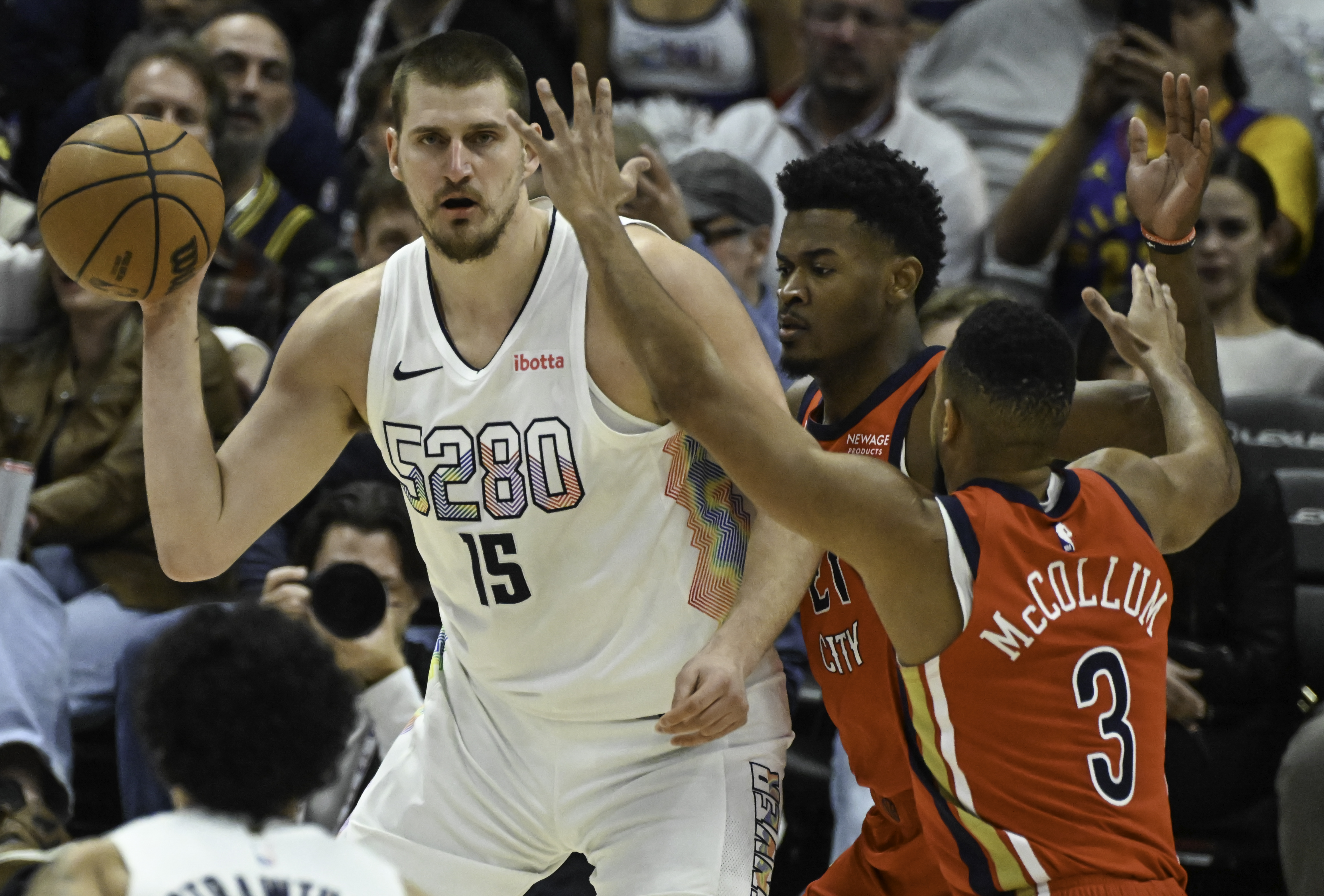 Denver Nuggets center Nikola Jokic (15) passes the ball while being defended by Pelicans Yves Missi and CJ McCollum during a game at Ball Arena on Wednesday, Feb. 5, 2025. The Nuggets defeated the Pelicans 144-119. (Jerilee Bennett,The Gazette)
