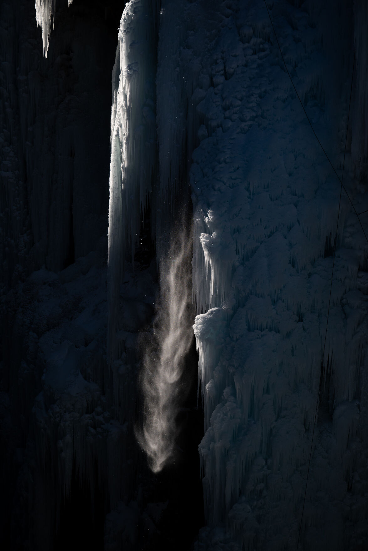 Falling snow and ice loosened by a climber is illuminated by morning sunshine as it falls into the Uncompahgre Gorge on Friday, Jan. 24, in Ouray, Colo. (Parker Seibold, The Gazette) (Parker Seibold)