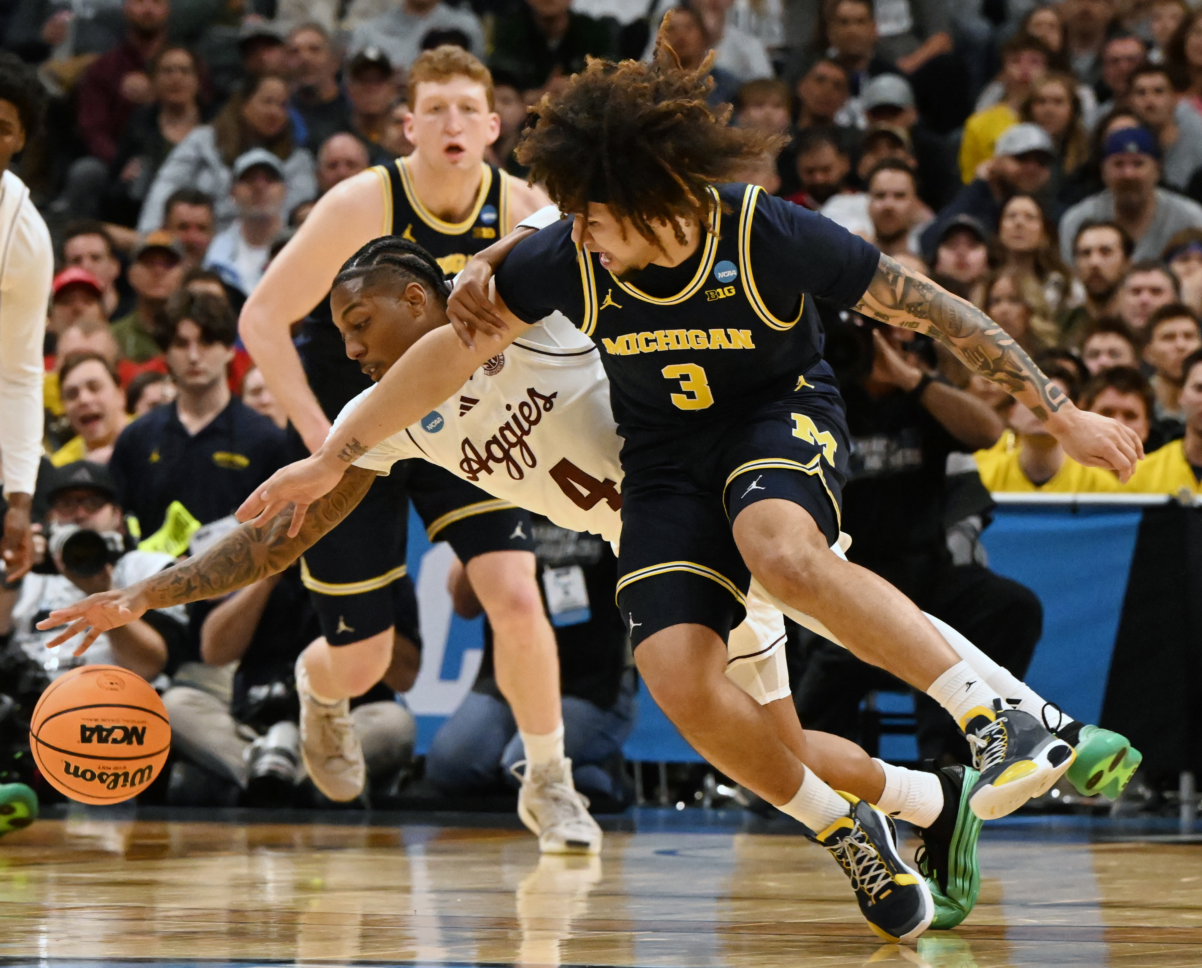 Michigan Wolverines guard Tre Donaldson (3) and Texas A&M Aggies guard Wade Taylor IV (4) fight for the ball during the first half of the second round of March Madness at Ball Arena on Saturday, March 22, 2025. Michigan won the game 91-79 and will be going to the Sweet Sixteen. (Jerilee Bennett,The Gazette)