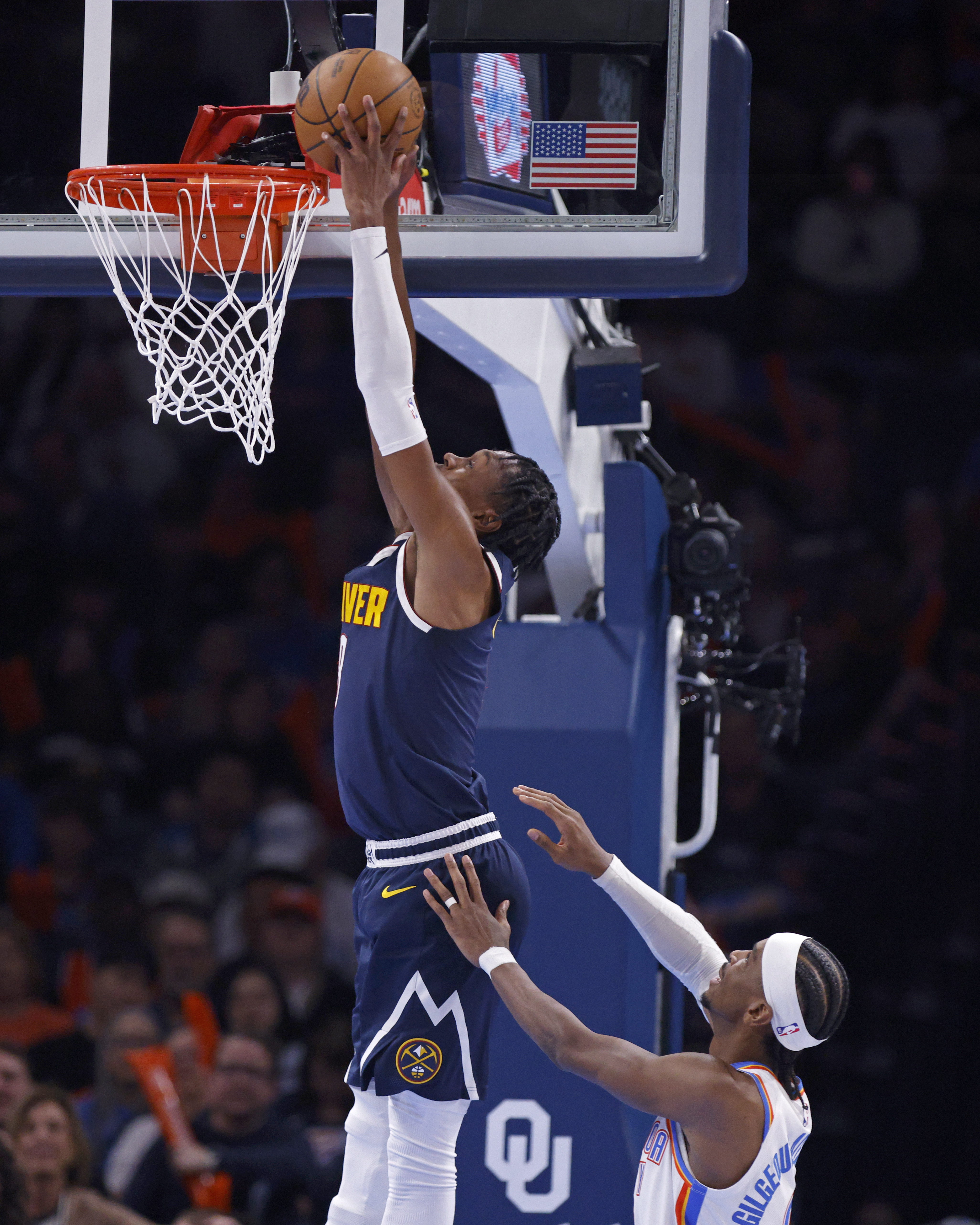 Nuggets forward Peyton Watson, top, goes up for a dunk over Oklahoma City Thunder guard Shai Gilgeous-Alexander during the first half of Monday night's game in Oklahoma City. (The Associated Press)