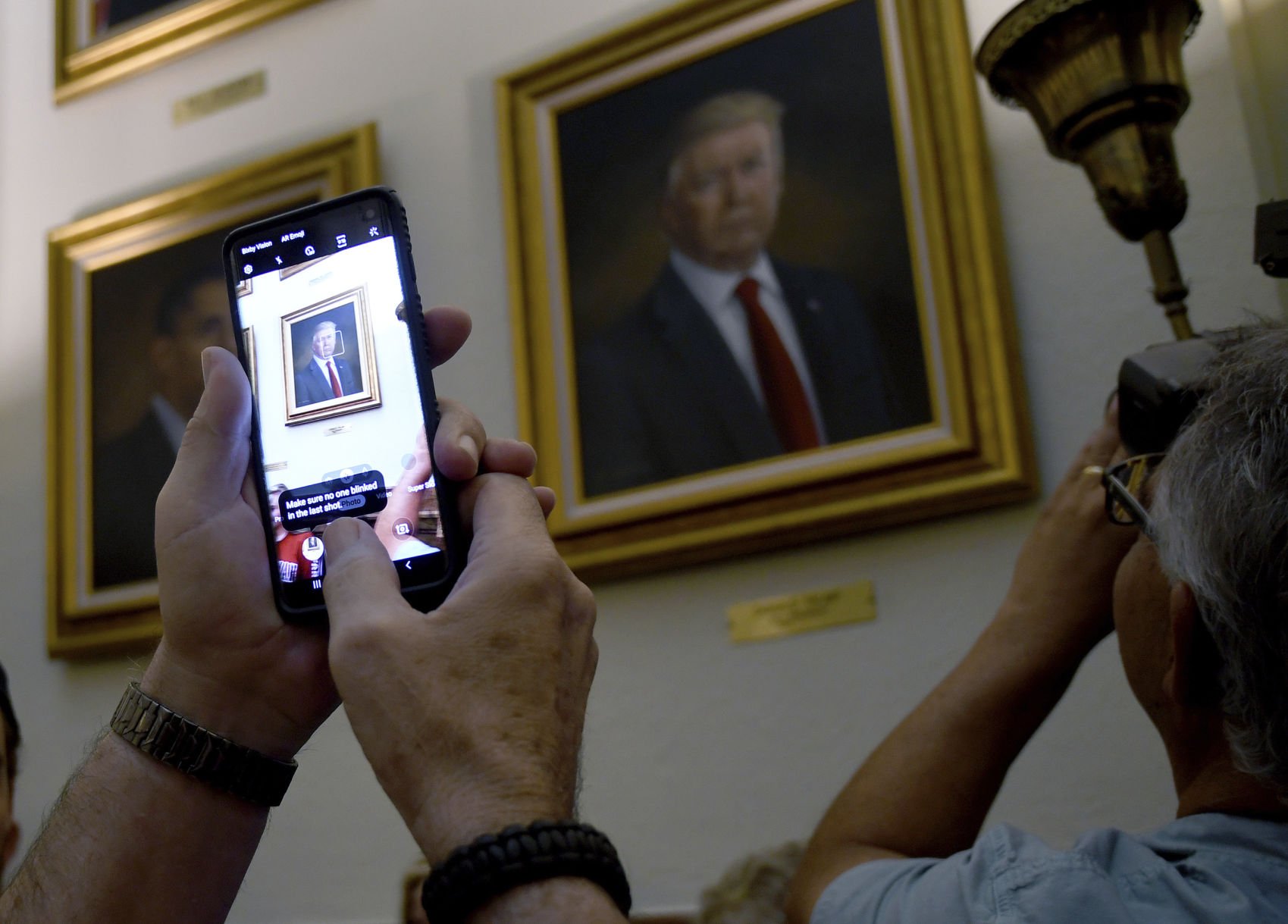 People take photos of President Donald Trump's portrait hanging in the Colorado Capitol after an unveiling ceremony Thursday, Aug. 1, 2019, in Denver. Colorado Republicans raised more than $10,000 through a GoFundMe account to commission the portrait, which was painted by Sarah Boardman, an artist who also produced the Capitol's portrait of President Barack Obama. (AP Photo/Thomas Peipert) (Thomas Peipert)