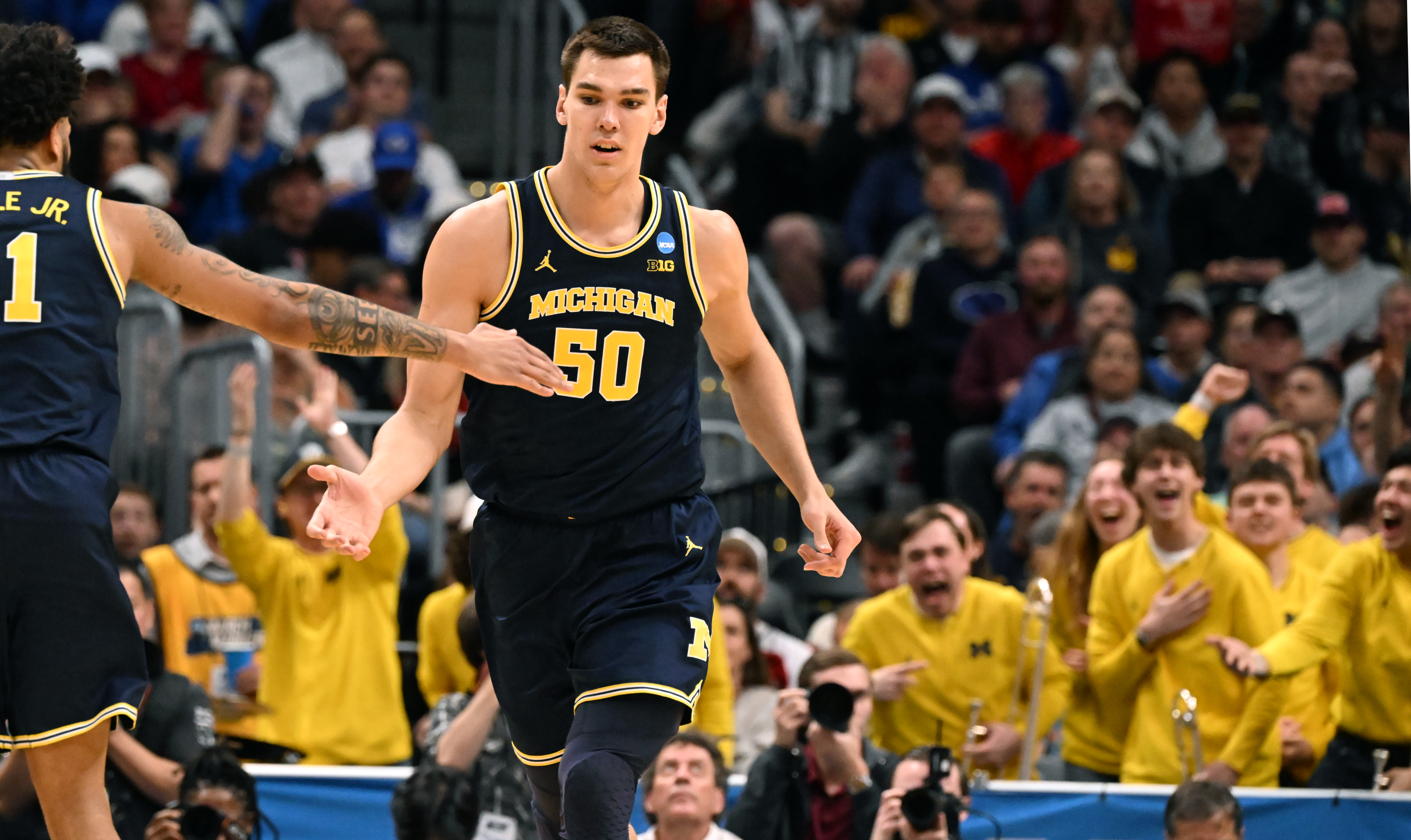 Michigan Wolverines center Vladislav Goldin (50) gets congrats from Michigan Wolverines guard Roddy Gayle Jr. (11) as Michigan fans go wild in the background during the second half of the second round of March Madness at Ball Arena on Saturday, March 22, 2025. Michigan won the game 91-79 and will be going to the Sweet Sixteen. (Jerilee Bennett,The Gazette)