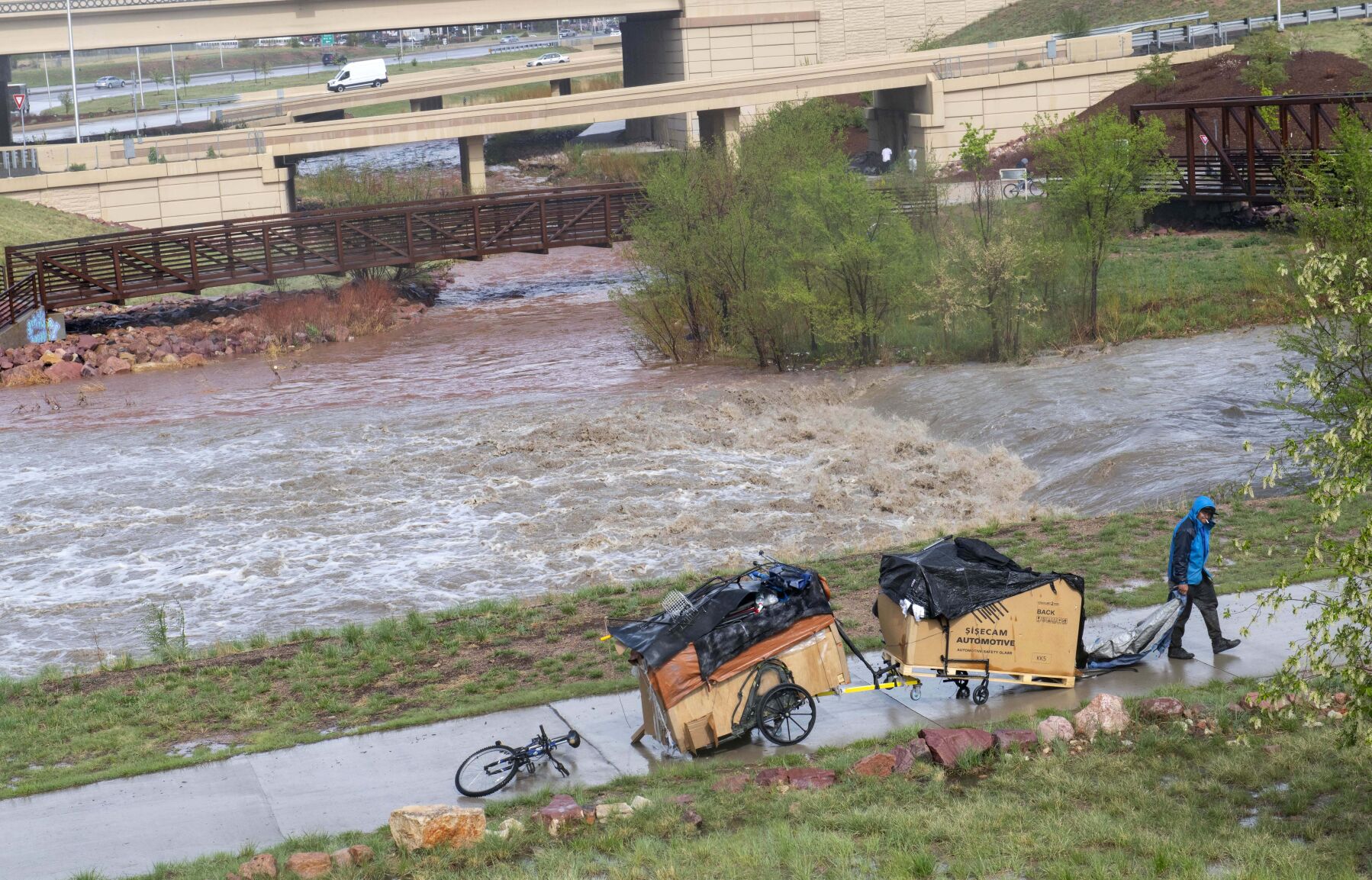 A homeless man grabs a tarp from his belongings after moving to higher ground as the Monument and Fountain creeks near flood level on May 11, 2023. (Christian Murdock, The Gazette)