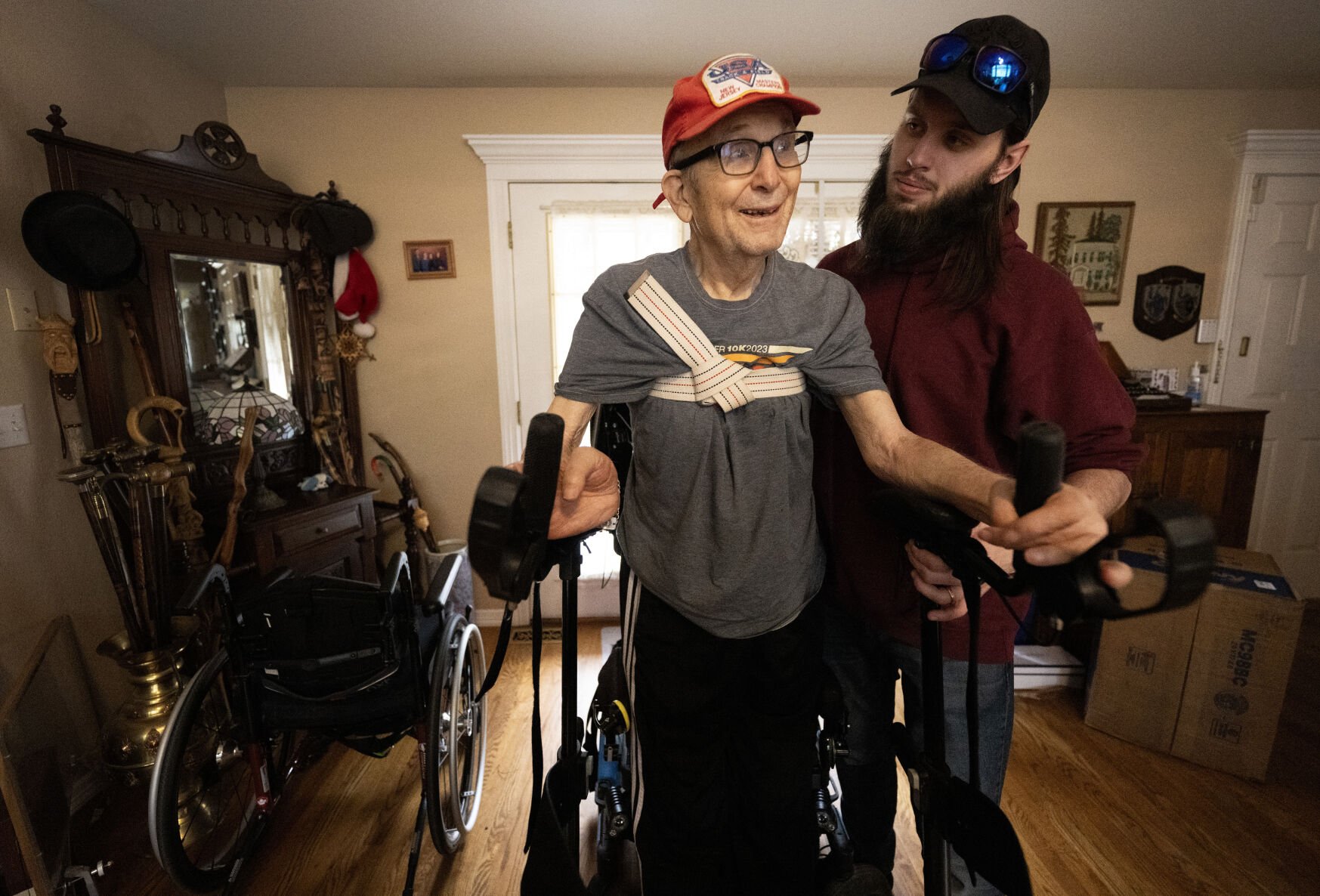 Caregiver John Bright helps Mark, 89, stand from his wheelchair at his Monument, Colo., home Friday, April 25, 2025. The Army veteran broke his neck cycling about five years ago and is happy with the care the VA has provided him. He is worried how staff cuts could hurt other veterans with severe injuries. Mark needs caregivers most of the day and into the night, seven days a week. The Gazette, Christian Murdock (Christian Murdock, The Gazette)