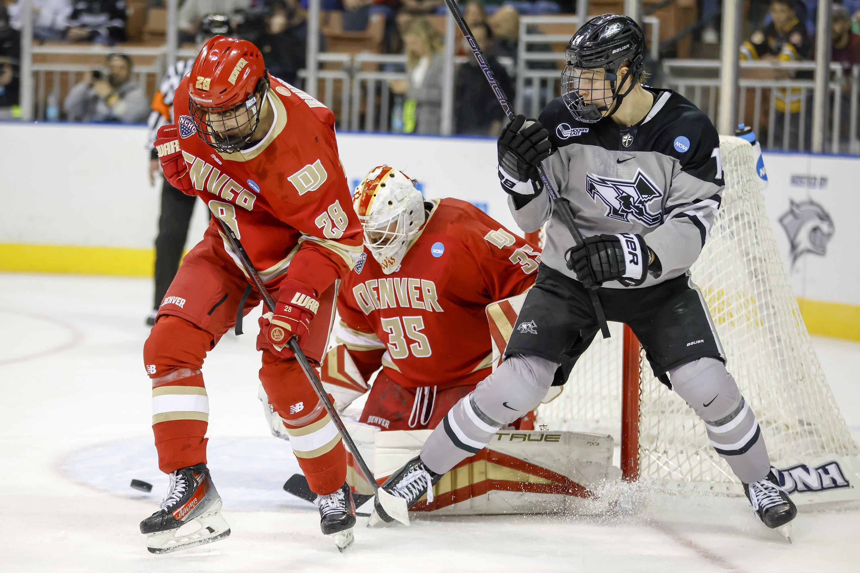 Denver defenseman Zeev Buium (28) defends Providence forward Aleksi Kivioja (14) in front of goalie Matt Davis (35) during the first period of an NCAA hockey regionals on Friday, March 28, 2025, in Manchester, N.H. (AP Photo/Greg M. Cooper) (Greg M. Cooper)