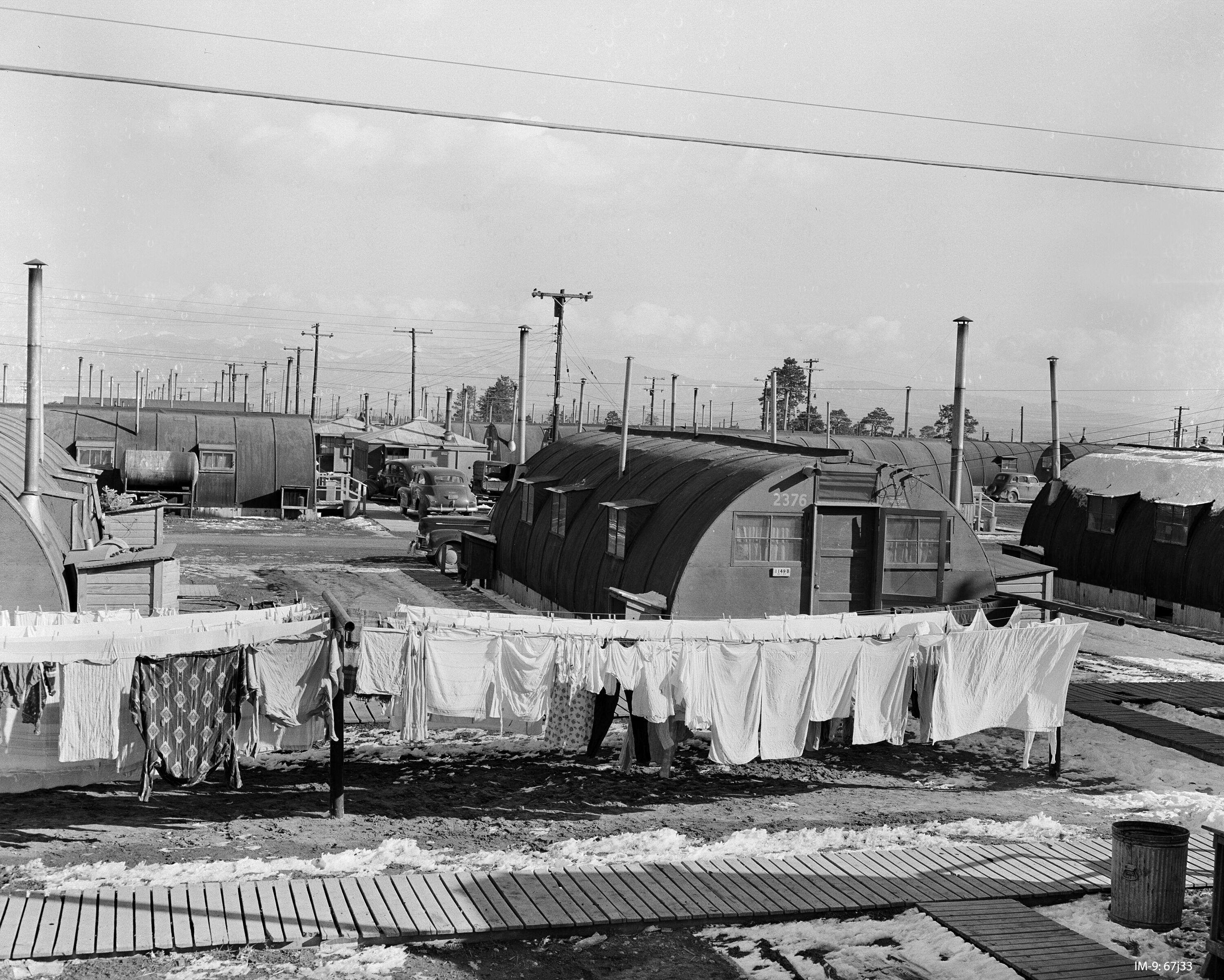In this Dec. 24, 1947, photo, a neighborhood of Quonset huts with laundry hanging outside sit on dirt lots with wooden walkways at Los Alamos.