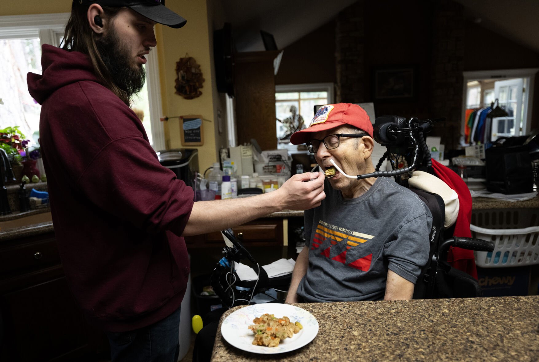 Caregiver John Bright feeds Mark (didn’t want to give his last name), 89, lunch at his Monument home Friday. The Vietnam War veteran broke his neck cycling in Garden of the Gods Park about five years ago and is happy with the care the VA has provided him. (Christian Murdock, The Gazette)
