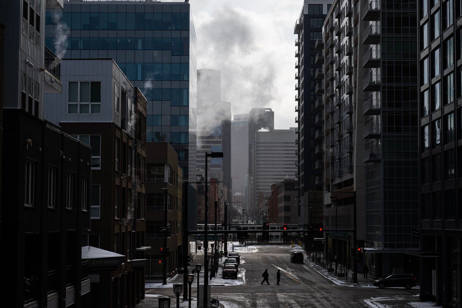 FILE PHOTO: Steam billows from buildings as pedestrians cross the street during a morning of single-digit temperatures on Monday, Jan. 30, 2023, in Denver, Colo. A proposed new rule from the Colorado Air Quality Control Commission would require all large building owners to increase energy efficiency and reduce carbon emissions. (TIMOTHY HURST/DENVER GAZETTE)