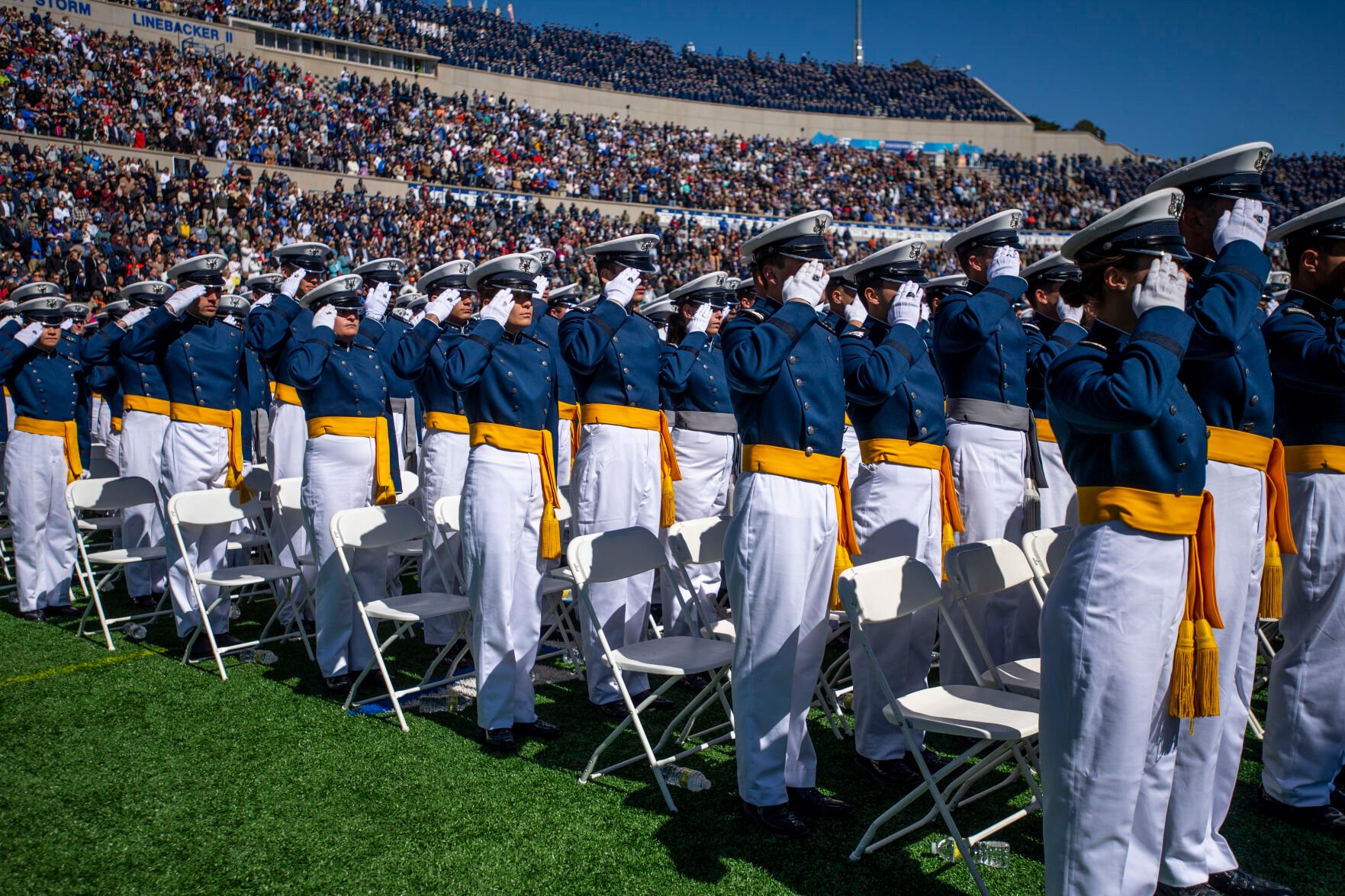Cadets stand and salute during the Air Force Academy graduation at Falcon Stadium on May 25, 2022. (Parker Seibold, Gazette file)
