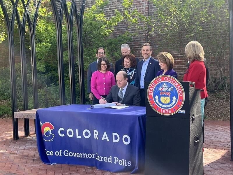 Gov. Jared Polis signs the budget as members of the Joint Budget Committee look on on April 28, 2025. (Marissa Ventrelli)
