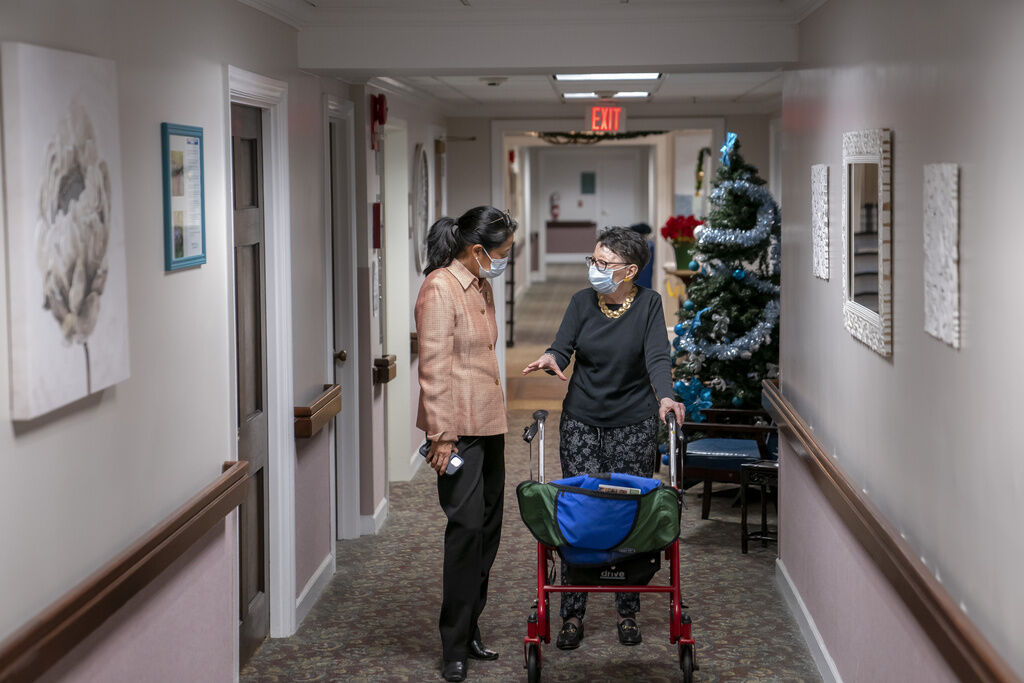 FILE PHOTO: Tina Sandri, CEO of Forest Hills of DC senior living facility, left, helps resident Courty Andrews back to her room, Dec. 8, 2022, in Washington. The federal government will, for the first time, dictate staffing levels at nursing homes, the Biden administration said Friday, Sept. 1, 2023, responding to systemic problems bared by mass COVID deaths. (AP Photo/Nathan Howard, File) (Nathan Howard/Associated Press)