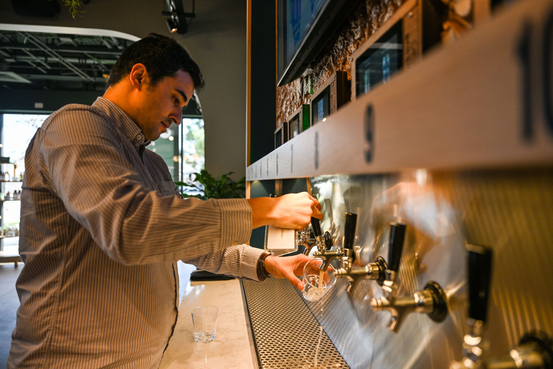 Damien Zouaoui, owner of Oakwell Beer Spa with his wife, Jessica (not pictured) pours a beer from one of the self-serve taps in the lobby of their new location in Highlands Ranch on Thursday, April 10, 2025. (Stephen Swofford, Denver Gazette) (StephenSwoffordPhotographerstephen.swofford@gazette.comhttps://secure.gravatar.com/avatar/1ddcaf11c5d70eaa58546ddc4e038687?d=mm&r=g)