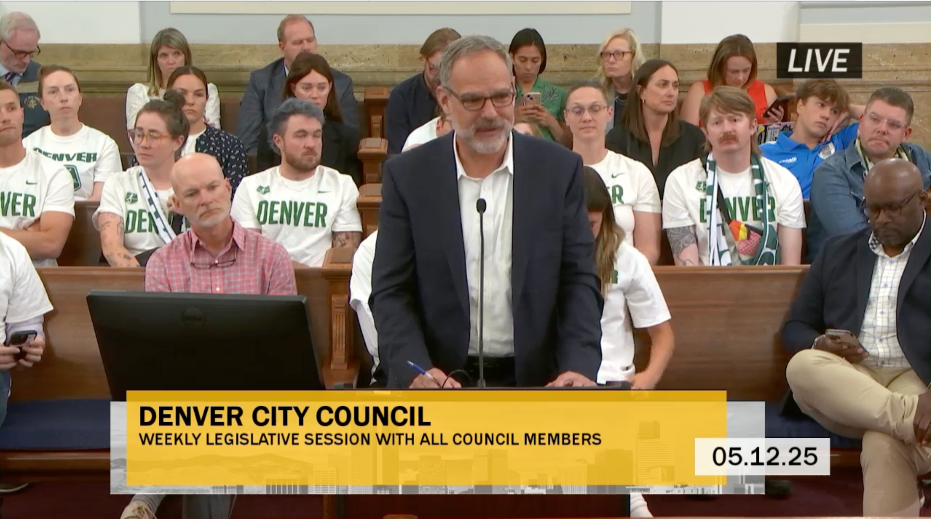 Supporters of Denver’s new NWSL franchise sport matching jerseys at Monday’s City Council meeting as Dan Barrett with CAA ICON, an outside consultant working with the franchise owners, offers remarks. (City of Denver screengrab)
