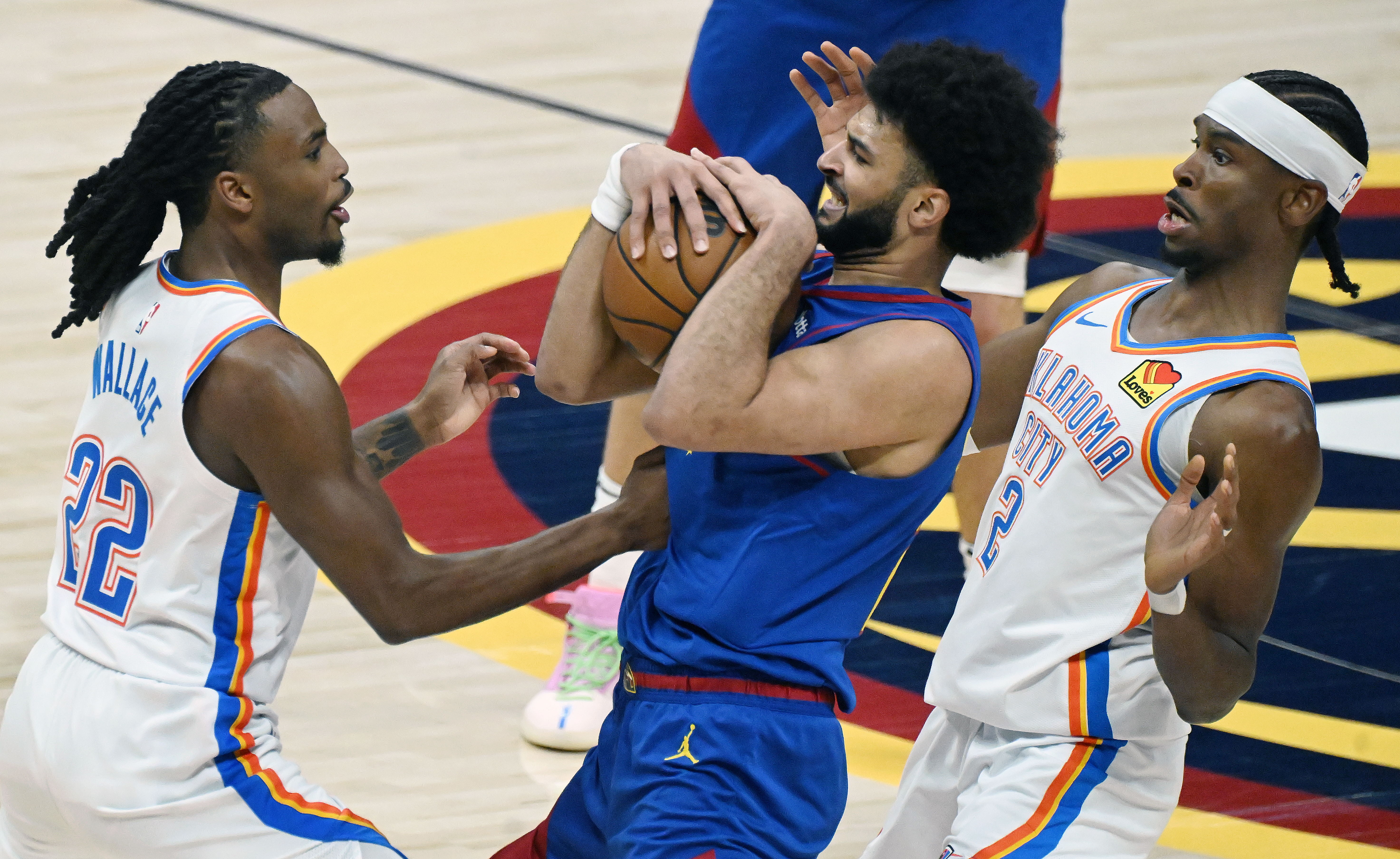 Denver Nuggets guard Jamal Murray (27) is sandwiched by Oklahoma City Thunder guard Cason Wallace (22) and Oklahoma City Thunder guard Shai Gilgeous-Alexander (2)l during the first quarter of game 3 of round 2 of the Western Conference Championship at Ball Arena on Friday, May 9, 2025. (Jerilee Bennett,The Gazette)
