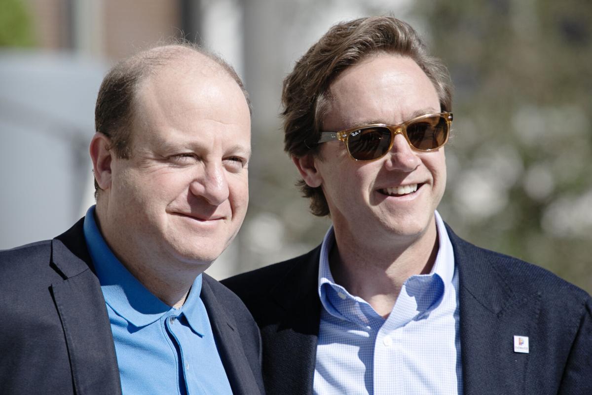 Gov. Jared Polis, left, and Mayor Mike Johnston listen to speakers announce details about the second annual Outside Festival