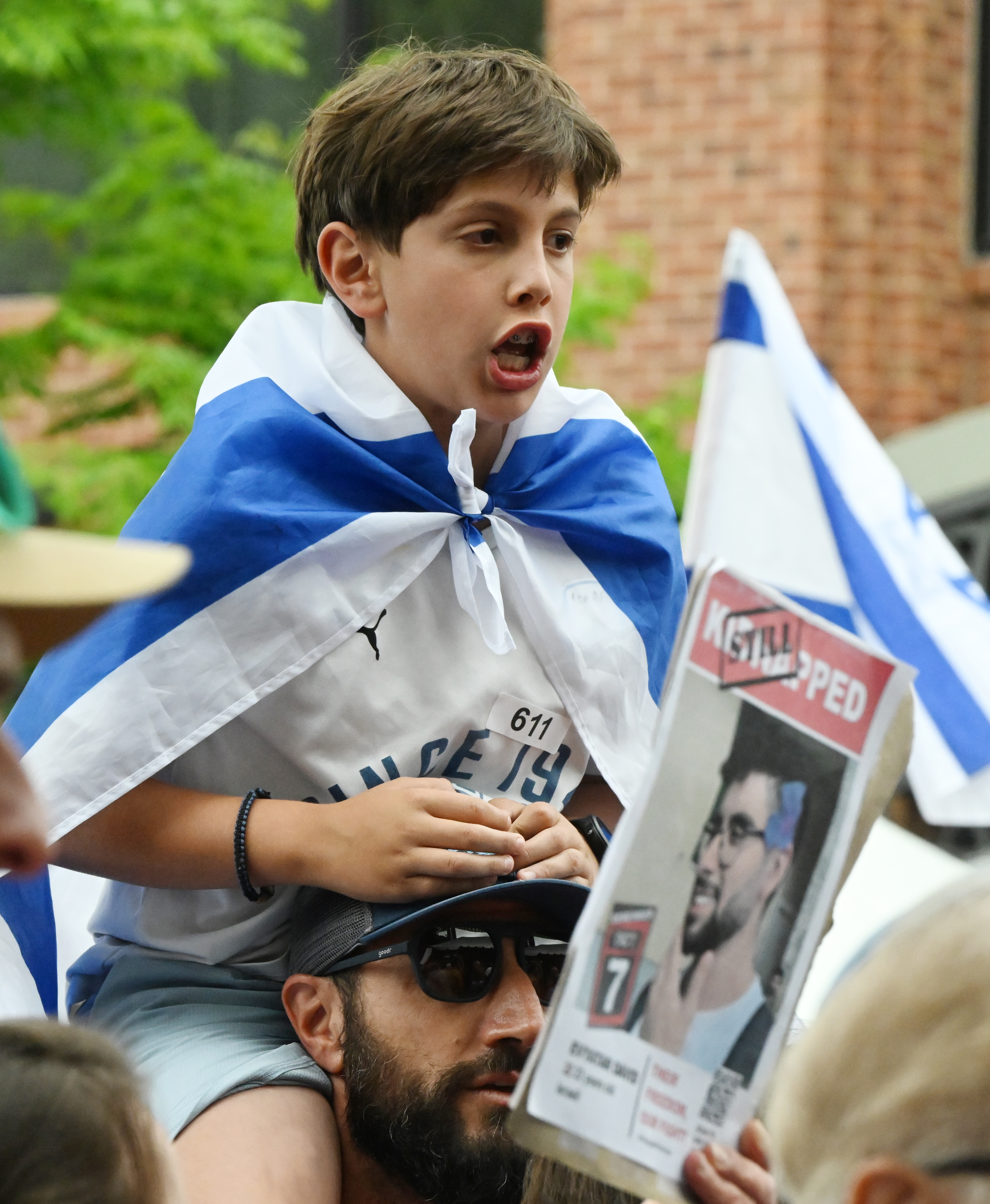 Wearing an Israeli flag, a young boy sings a Jewish song after participating in the Run For Their Lives walk . They walked in the same location as last week along the Pearl Street Mall on Sunday, June 8, 2025. Last weeks walk ended with a man using makeshift molotov cocktails to set the peaceful protesters on fire.