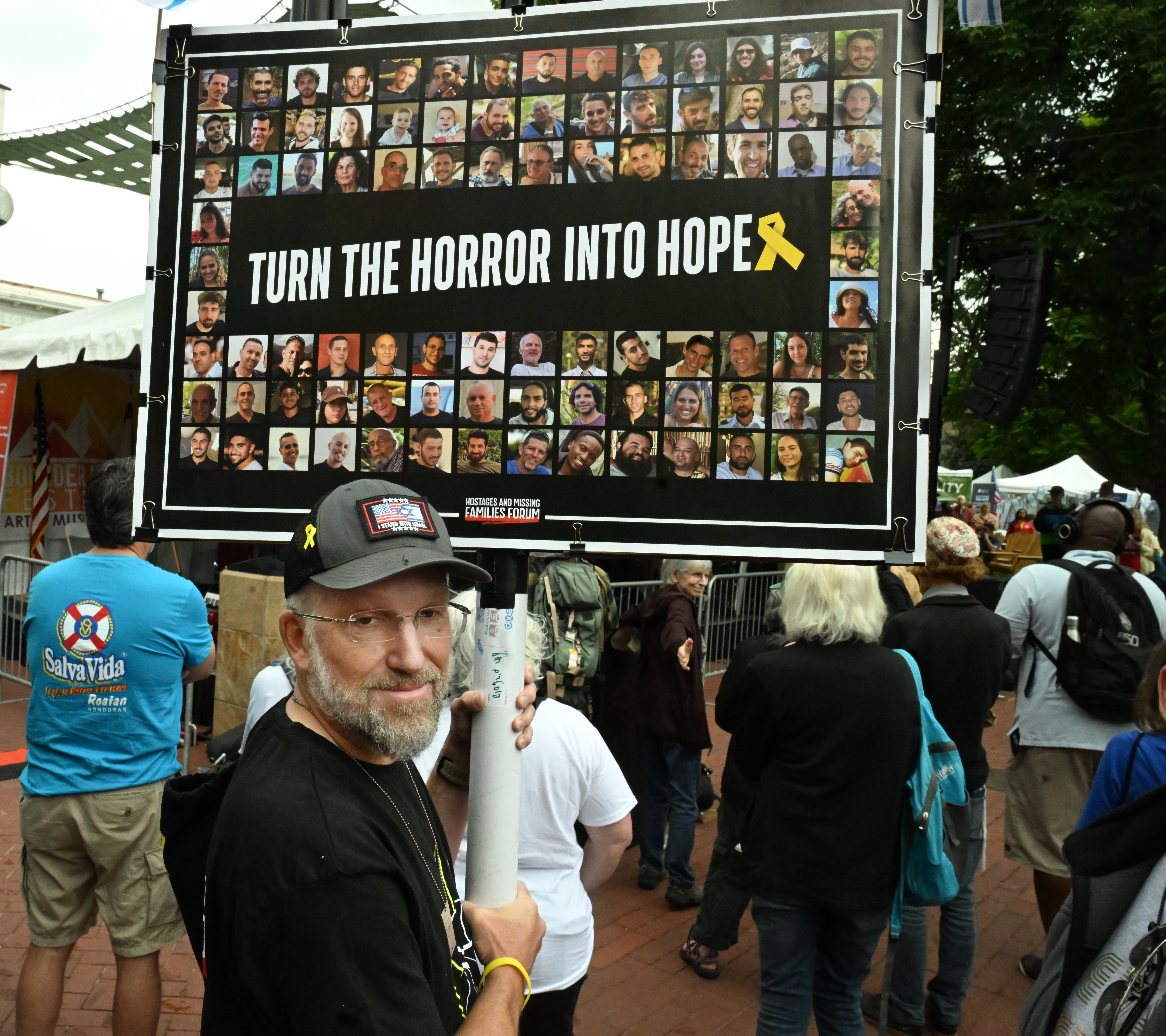 Daniel Markofsky carries a sign with a poster that he got in Israel when he was there last week. Markofsky was one of the hundreds that came out to participate in the Run for Their Lives walk to show resilience and solidarity in the face of the June 1 antisemitic terror attack. They walked the same walk that they did last week, but that ended in a man using makeshift molotov cocktails to set the peaceful protesters on fire.